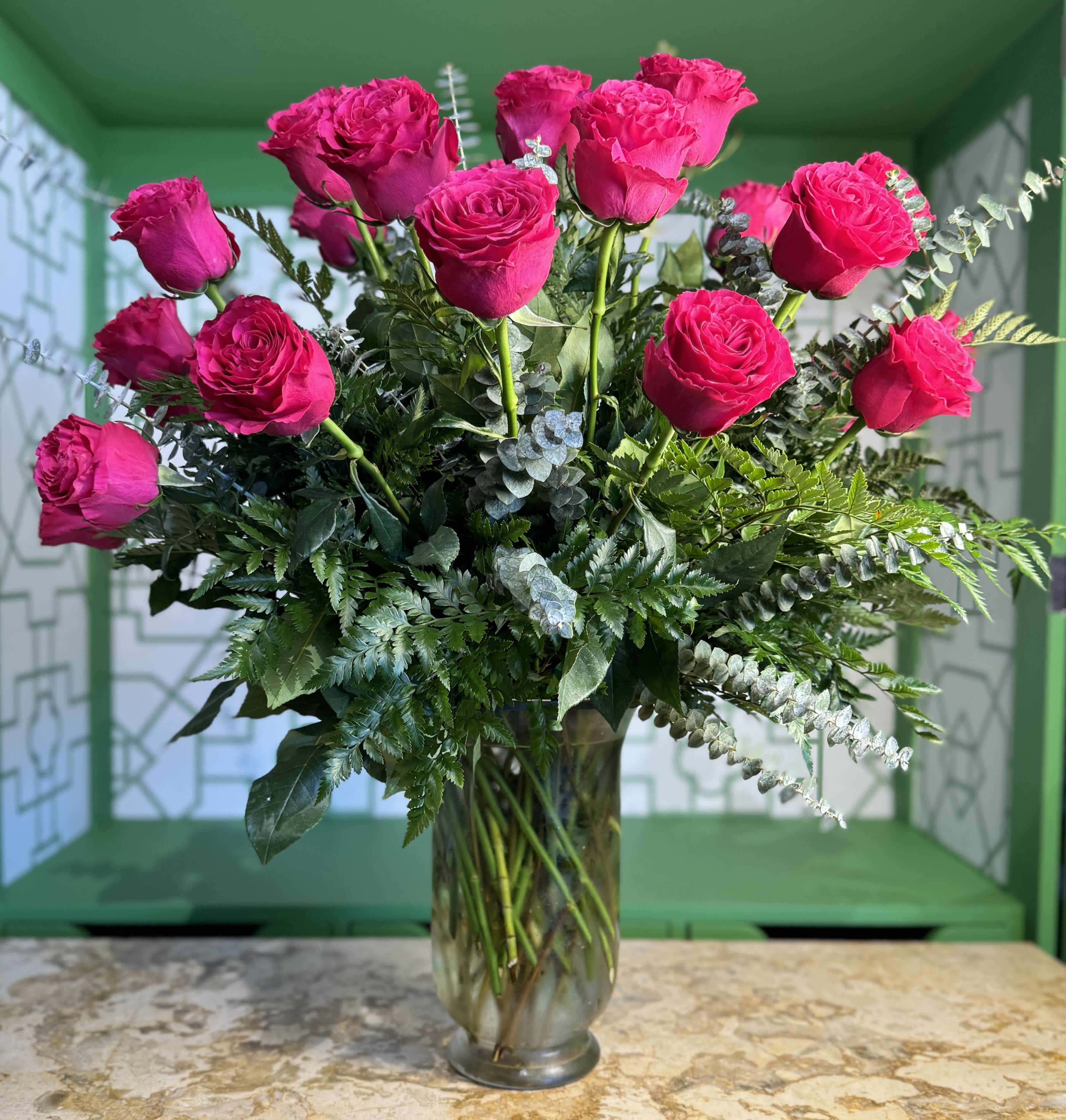 Pink roses arranged in a clear glass vase with mixed greenery