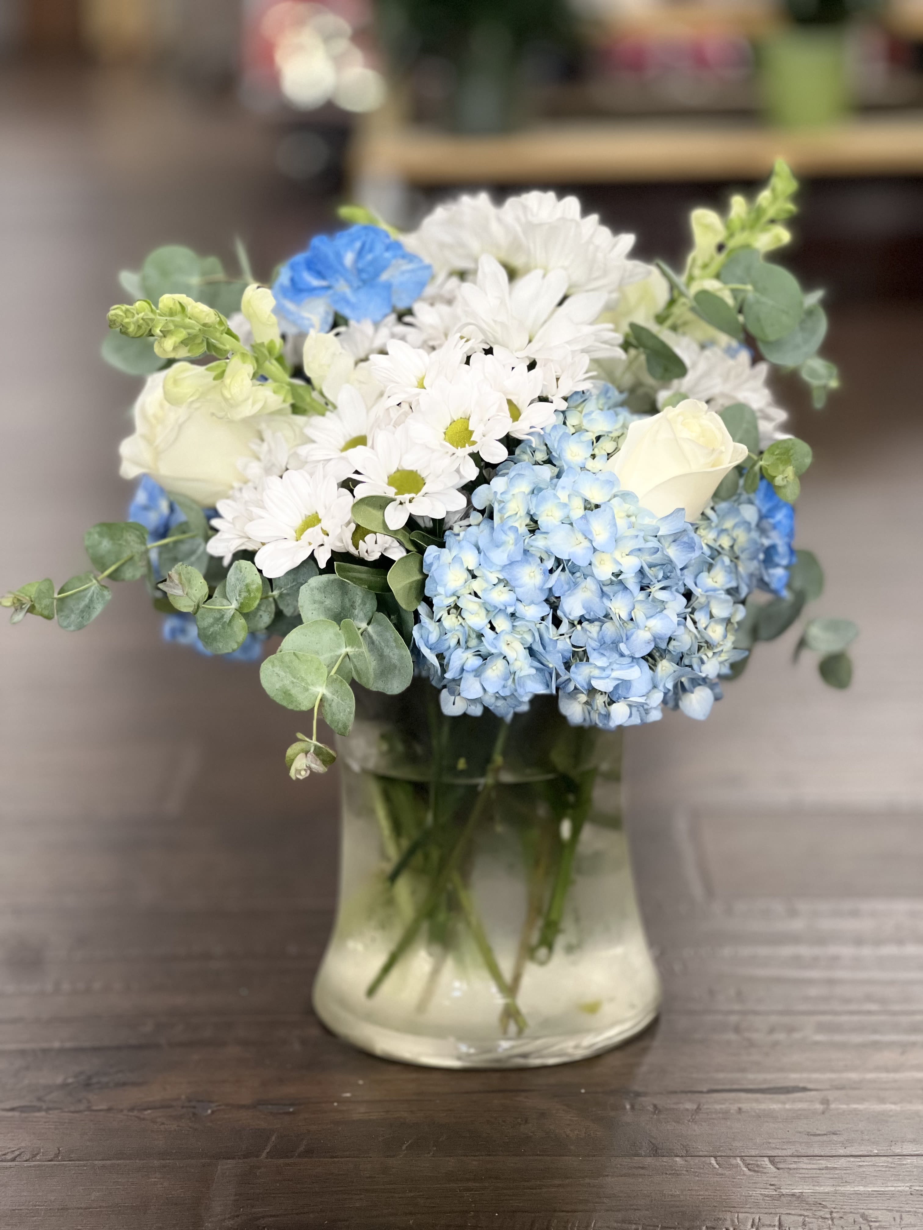 Blue hydrangeas and white daisies with roses in a glass vase