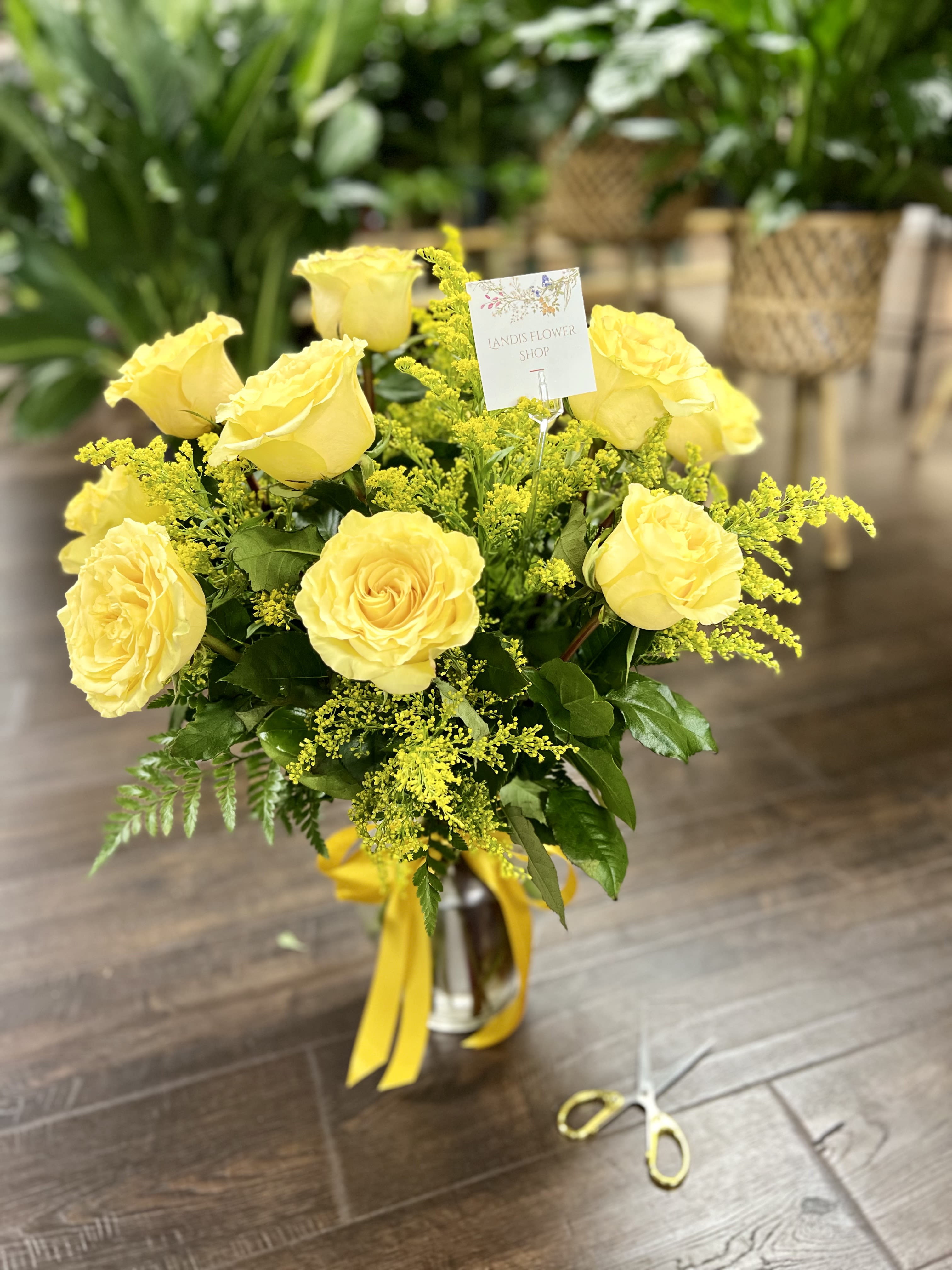 Yellow roses arranged in a glass vase with yellow ribbon
