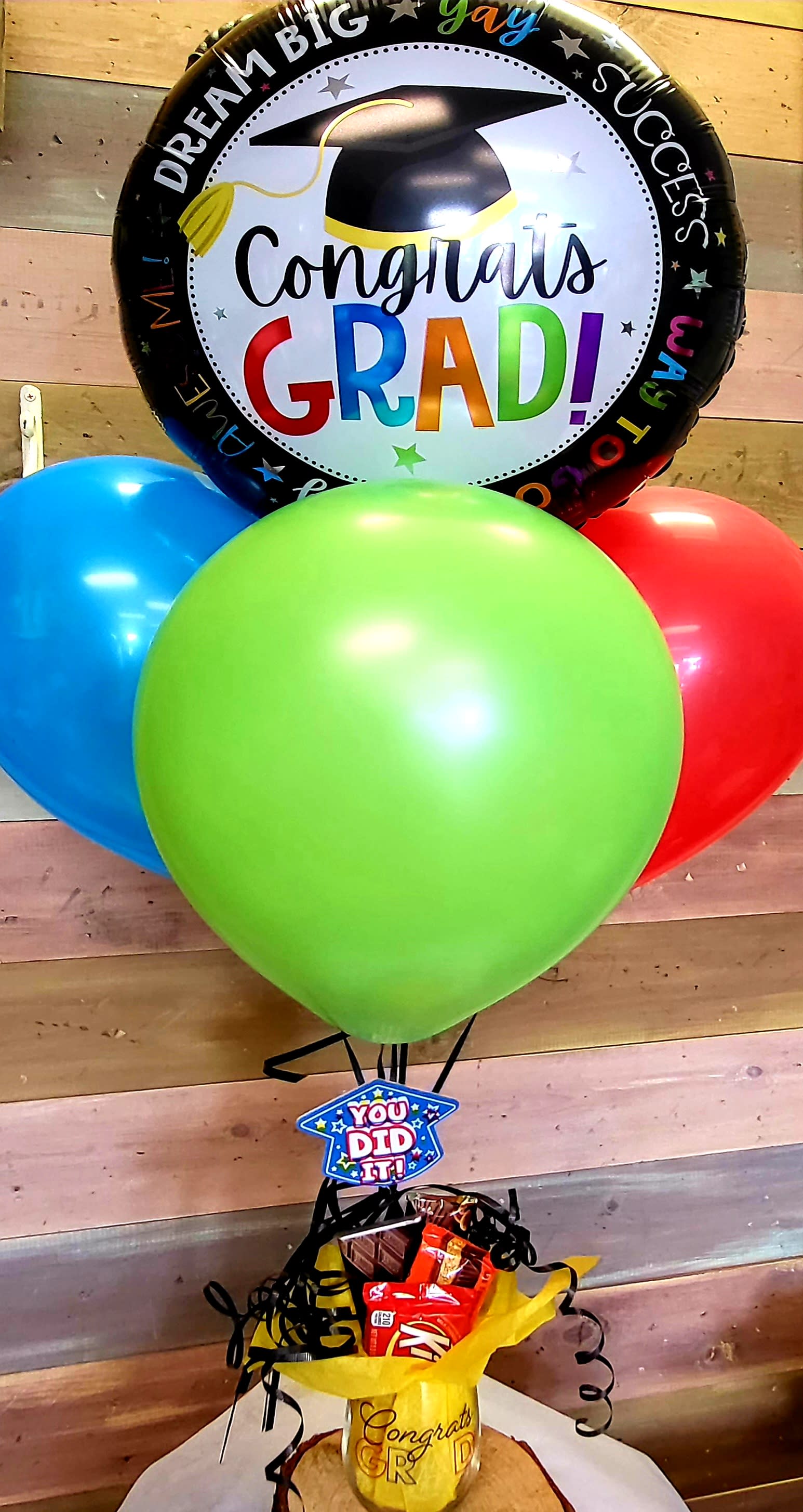 Graduation balloon bouquet with colorful balloons and candy in a gift cup