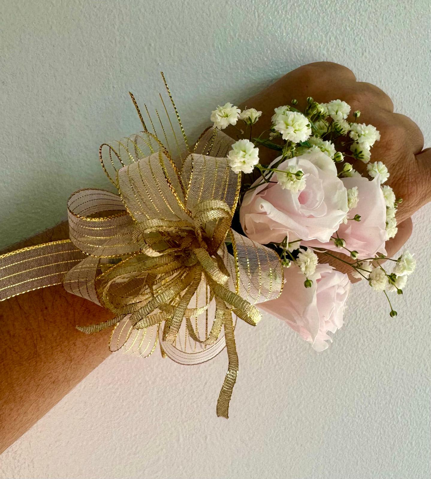 Small wrist corsage with pale pink roses and white baby's breath on gold ribbon
