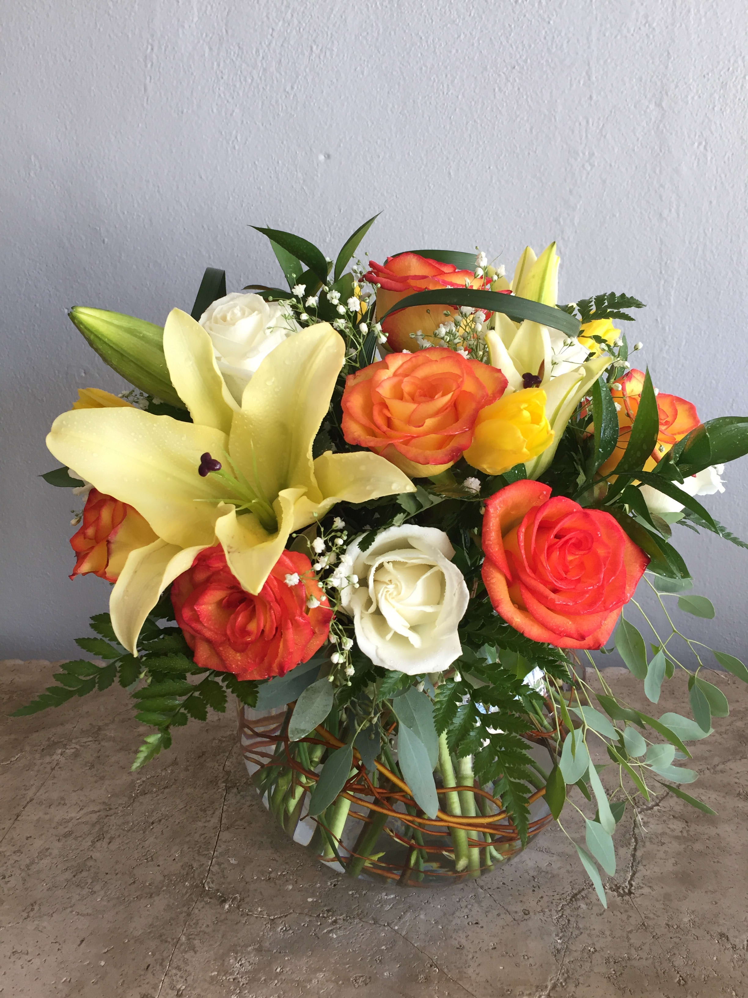Bouquet of orange and white roses with yellow lilies in a woven basket