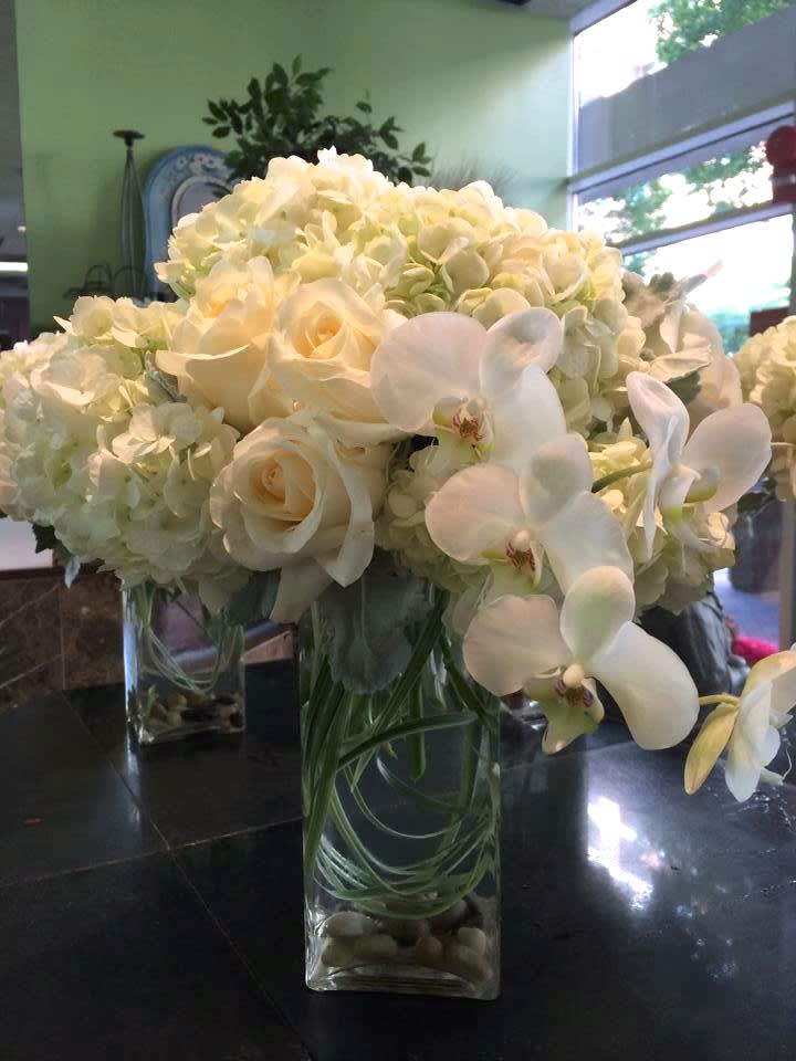 White roses and orchids arranged in a clear glass vase