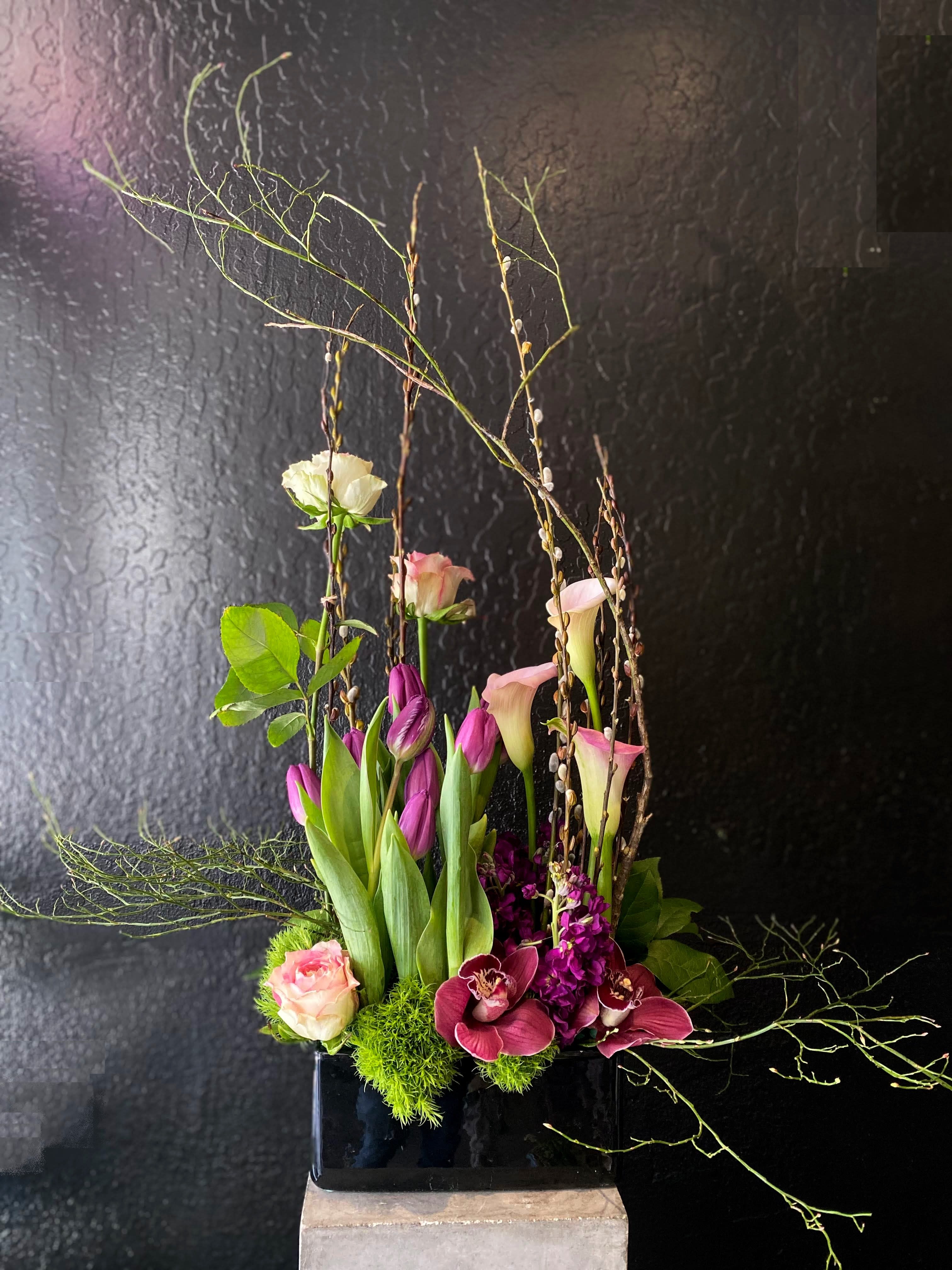 The Pat  - A composite design makes this arrangement look like it's growing.  Structured and beautiful in a ceramic container offers something different.  Pictured is our standard sizing. Container measures roughly 8" long. Some materials are seasonal and substitutions may apply. Due to rising heat tulips may be substituted.