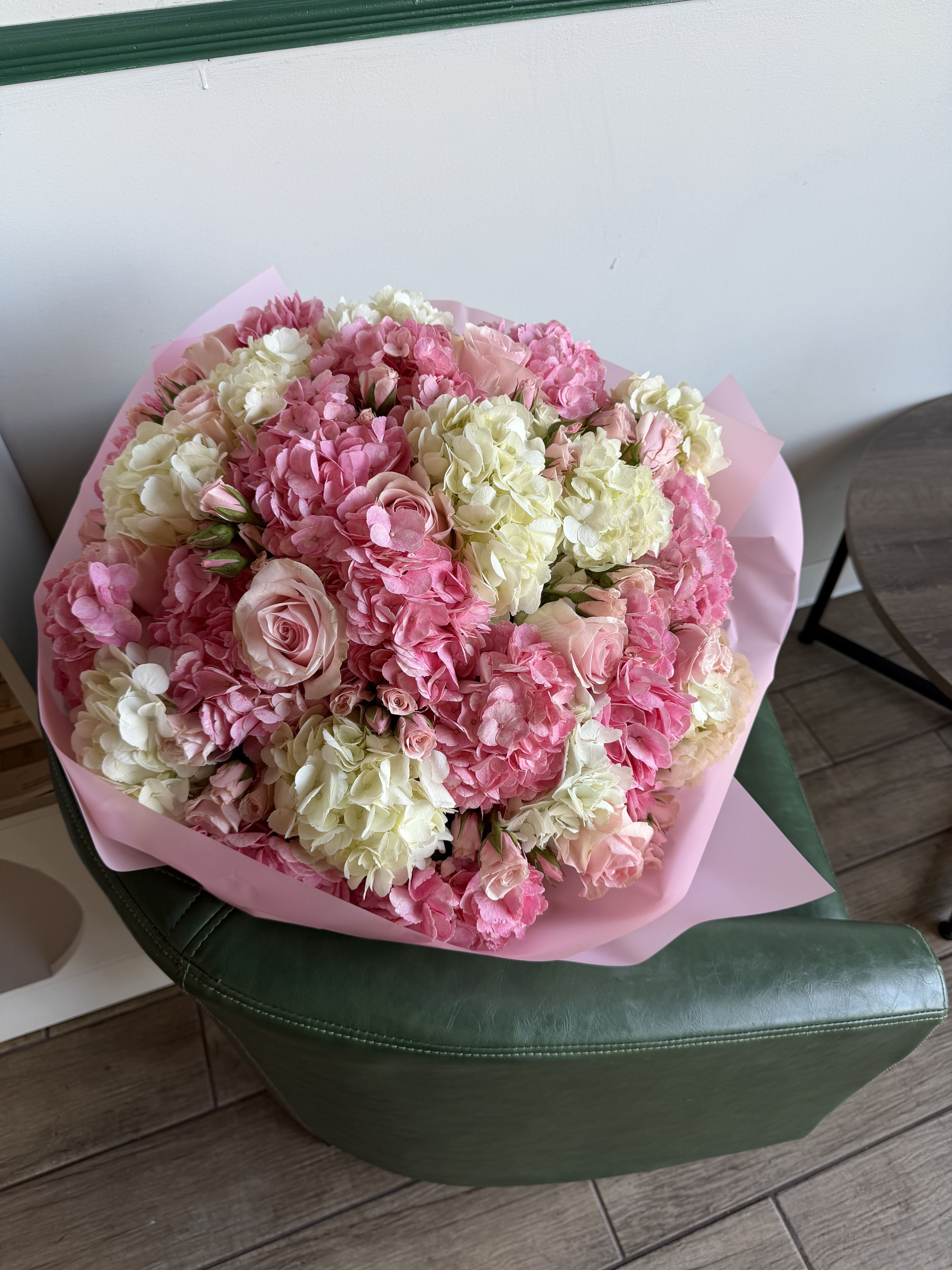 Large pink and white bouquet with roses and hydrangeas wrapped in pink paper
