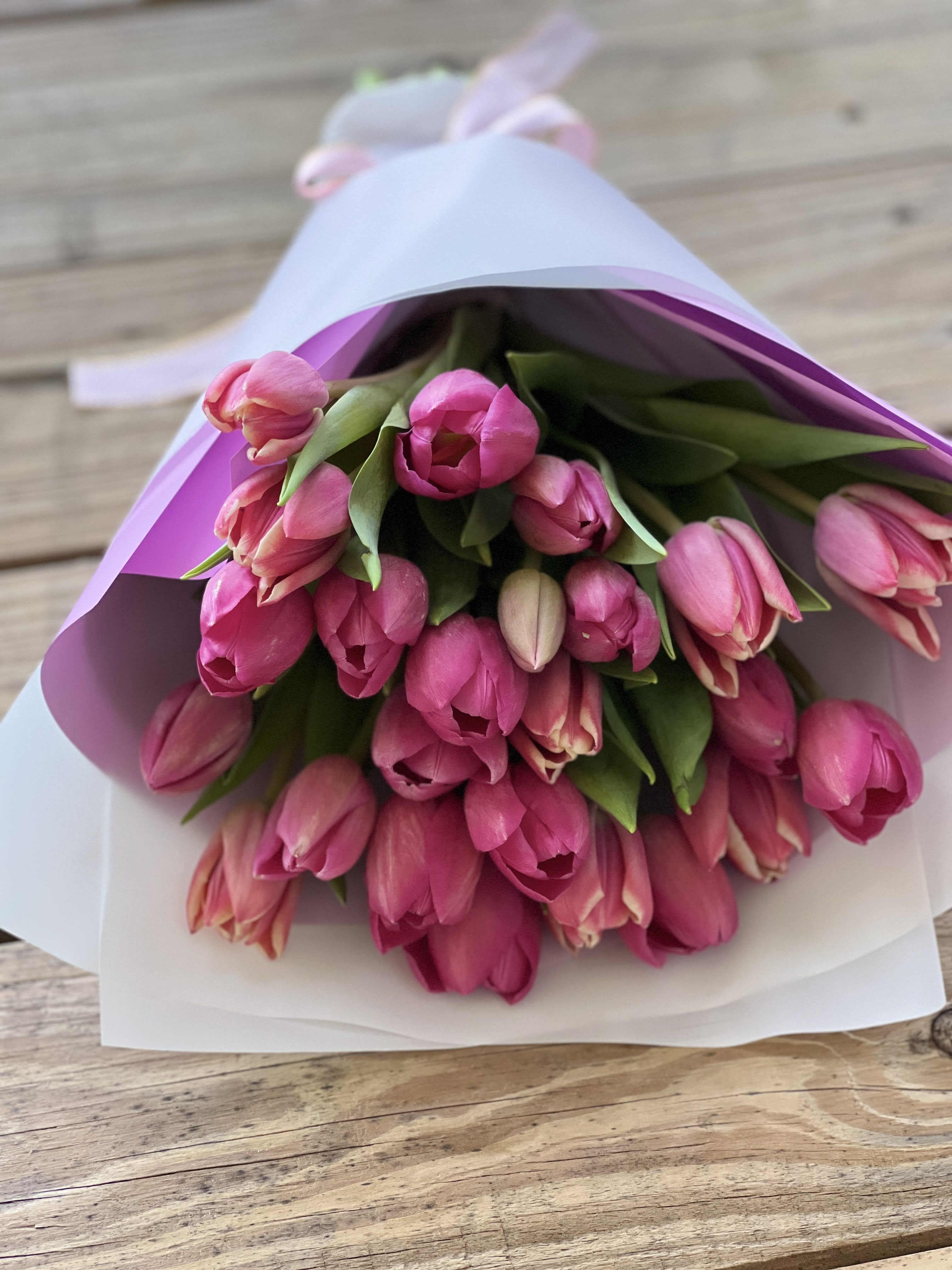 Bouquet of pink tulips wrapped in white and lavender paper