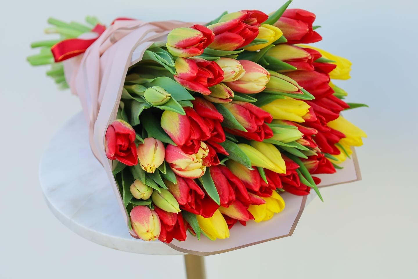 Bouquet of red, yellow, and pink tulips wrapped in pale paper
