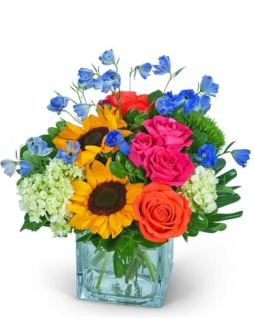 Colorful bouquet of roses, sunflowers, and blue flowers in a glass vase