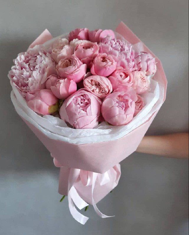 Pink bouquet of peonies and tulips wrapped in pastel paper