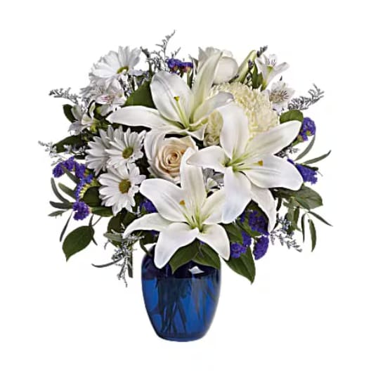 Beautiful in Blue - In this arrangement, the serenity of the color blue along with the purity of intention symbolized by white will let the family know you are sending your calm strength to them during these difficult times Blooms such as crème roses, graceful white oriental lilies, white alstroemeria, a white disbud mum, purple statice and lavender limonium are accented by seeded eucalyptus and salal in a stunning cobalt blue glass vase.