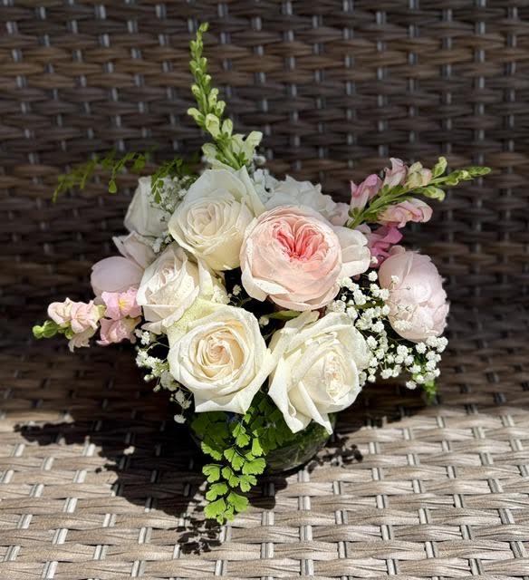 Garden Party - A low glass bowl is brimming with an assortment of pink and blush garden roses with snapdragons and an accent of filler and foliage. These smell like a walk in the garden!