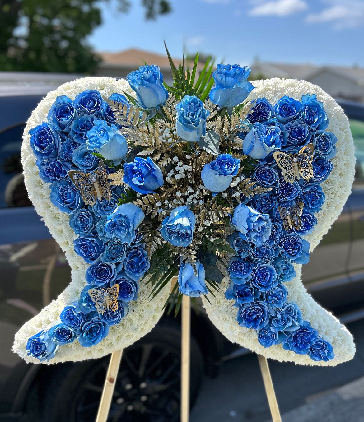 Blue rose funeral spray in a butterfly shape on an easel