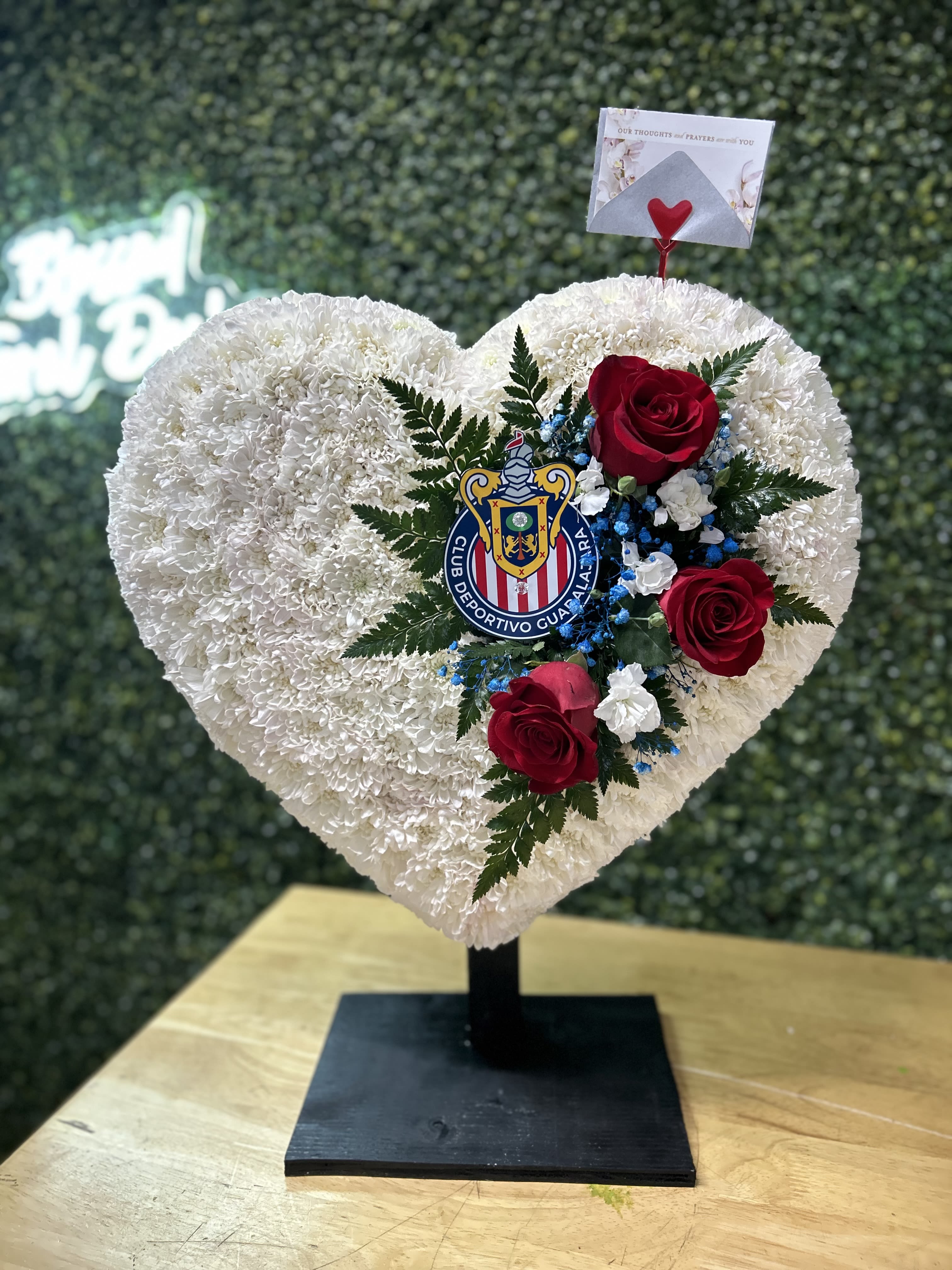 Heart-shaped white floral arrangement with red roses on a stand