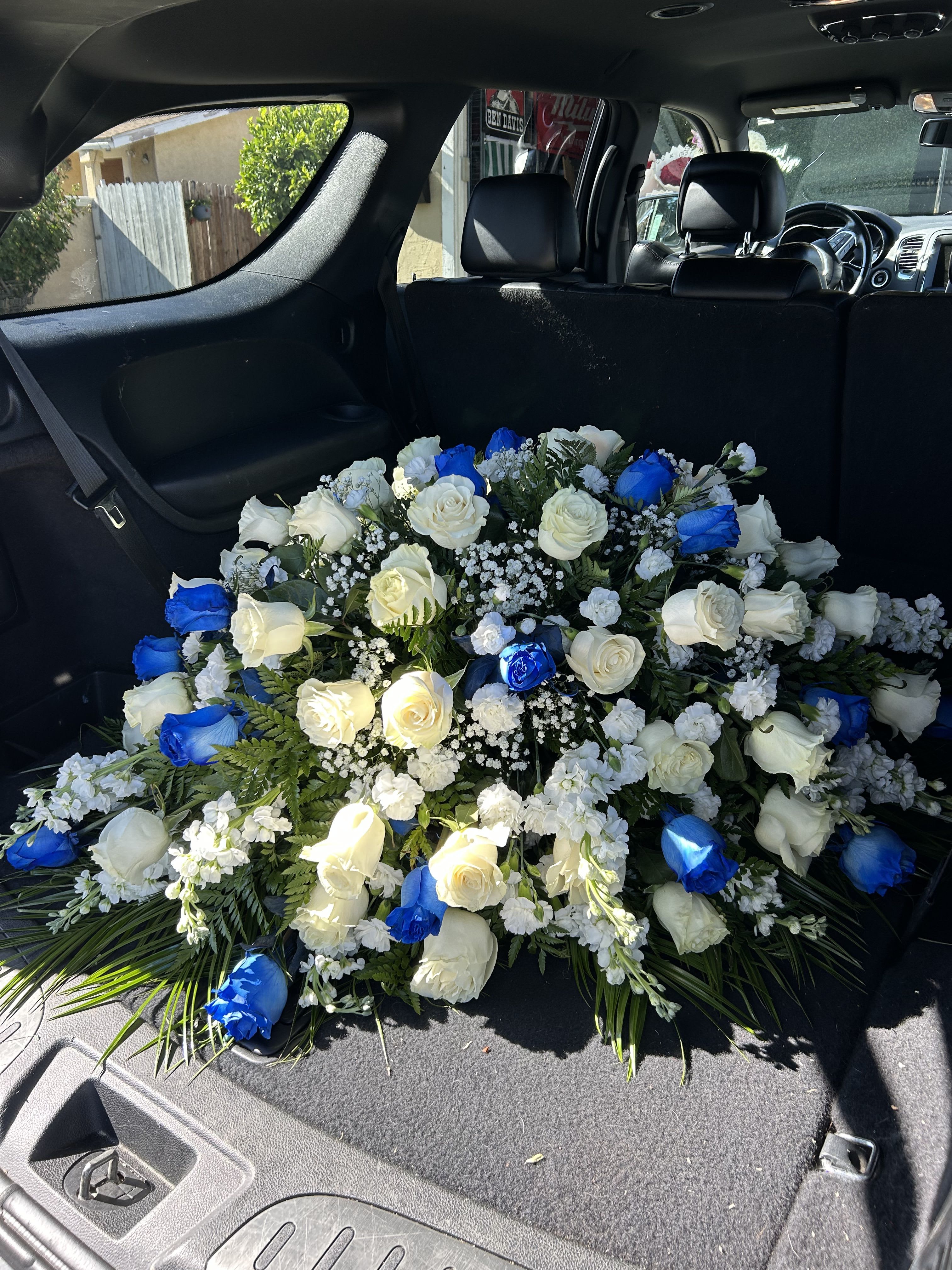 Large bouquet of white and blue roses arranged in a car cargo area
