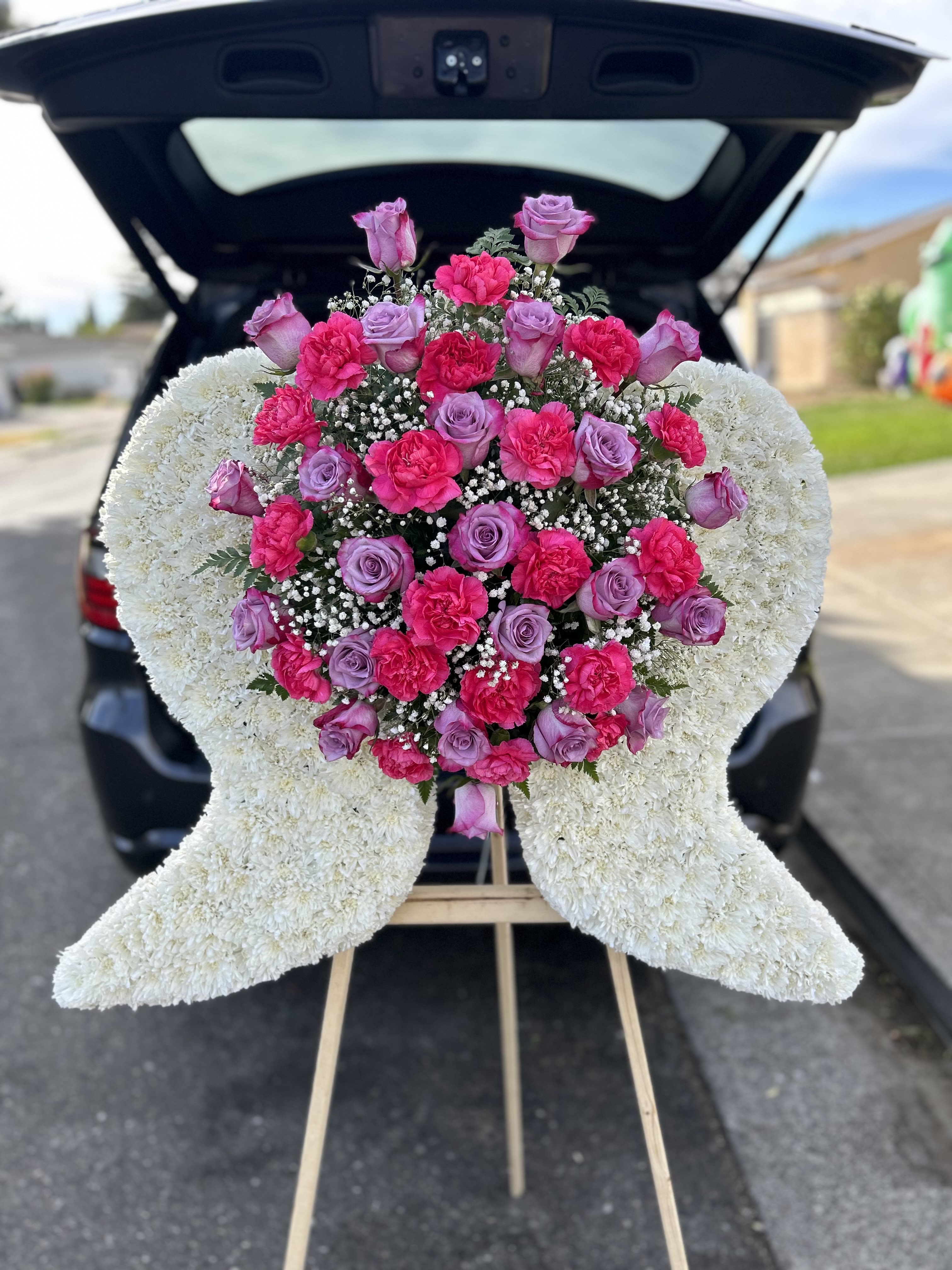 Heart-shaped floral spray with pink roses and carnations on an easel