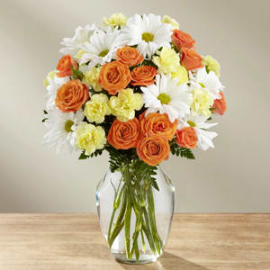 Orange roses and white daisies in a clear glass vase