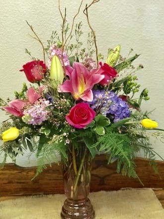 Mixed bouquet with pink lilies, roses, and purple hydrangeas in a glass vase
