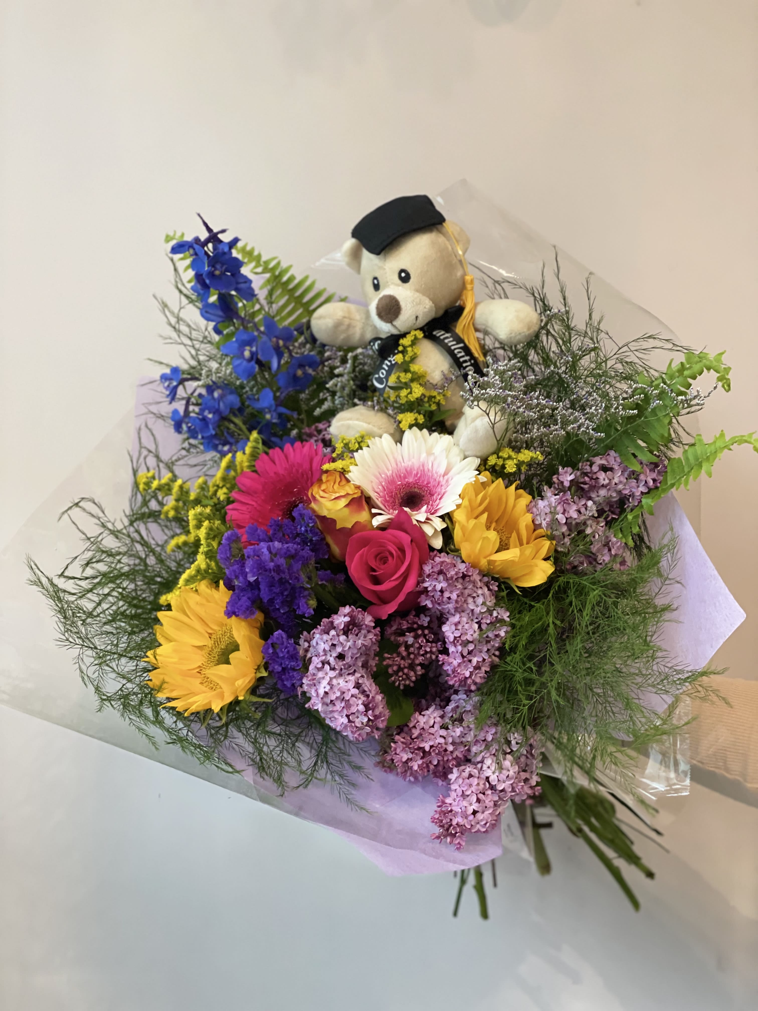 Bouquet of mixed flowers with a teddy bear in a graduation cap