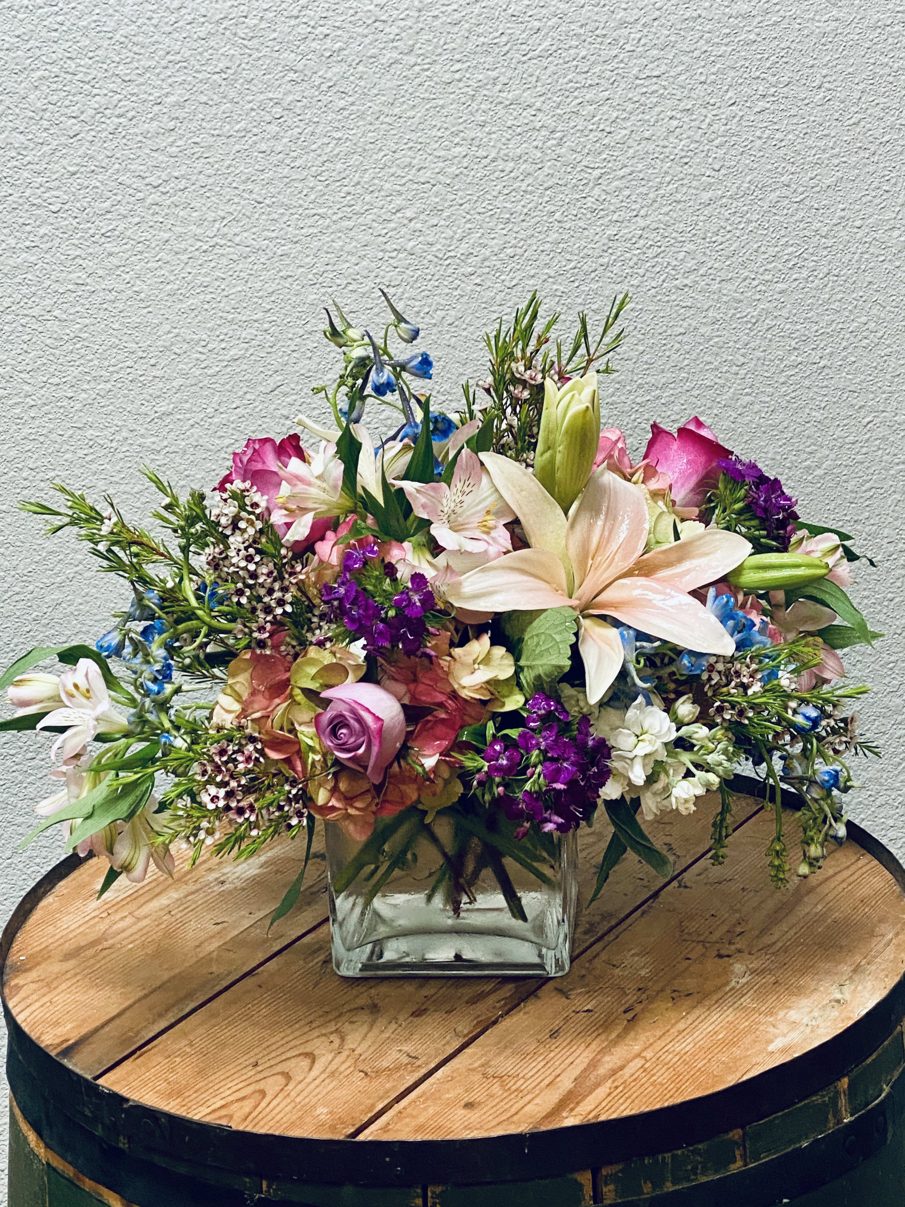 Mixed bouquet in a square glass vase with pink, white, and purple flowers