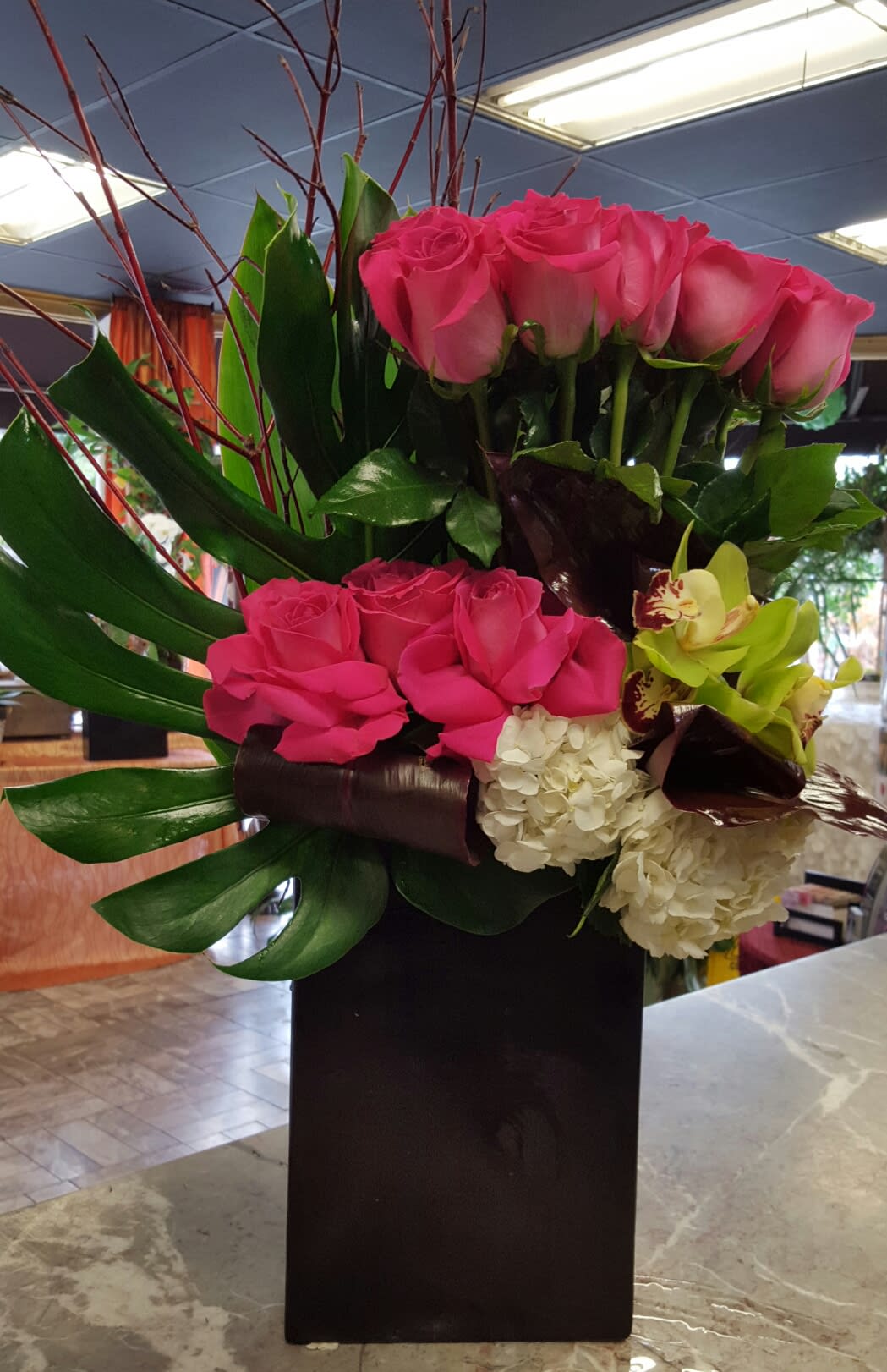 Pink roses and orchids arranged in a tall black vase