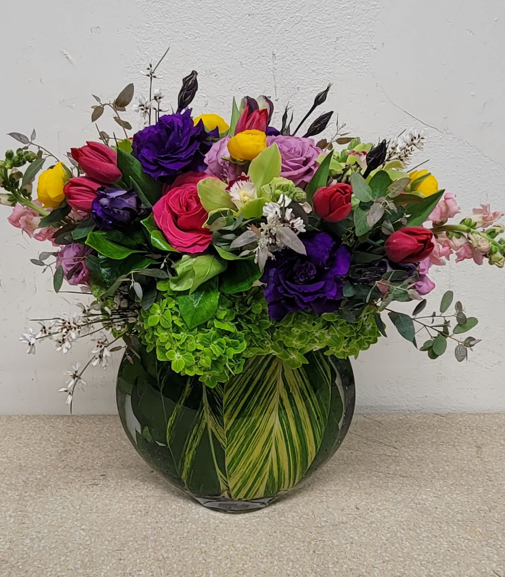 Mixed bouquet of colorful roses and tulips in a glass vase