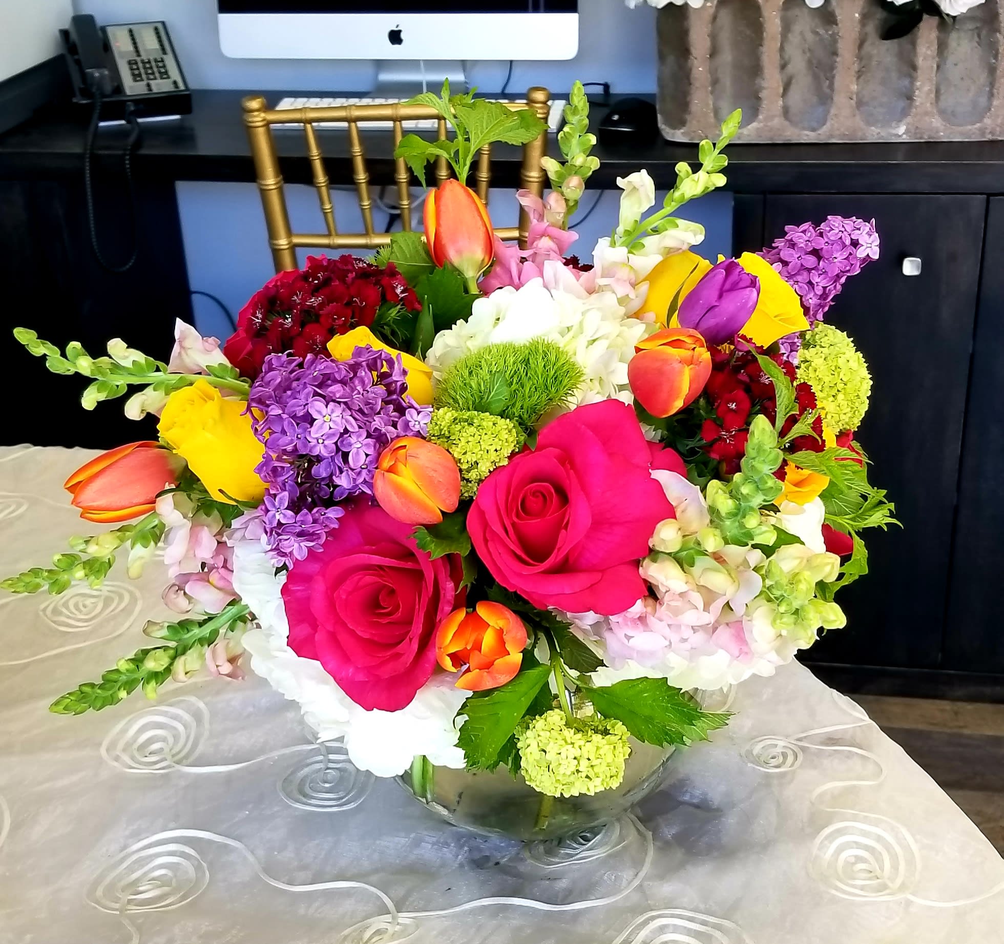 Bright mixed bouquet of roses, tulips, and hydrangea in a glass vase