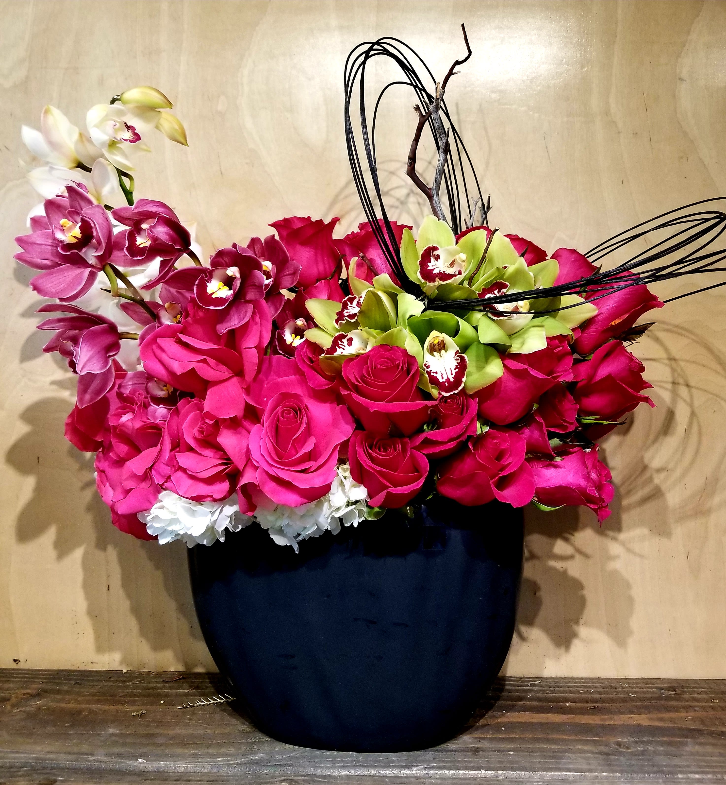Pink roses and orchids arranged in a dark vase