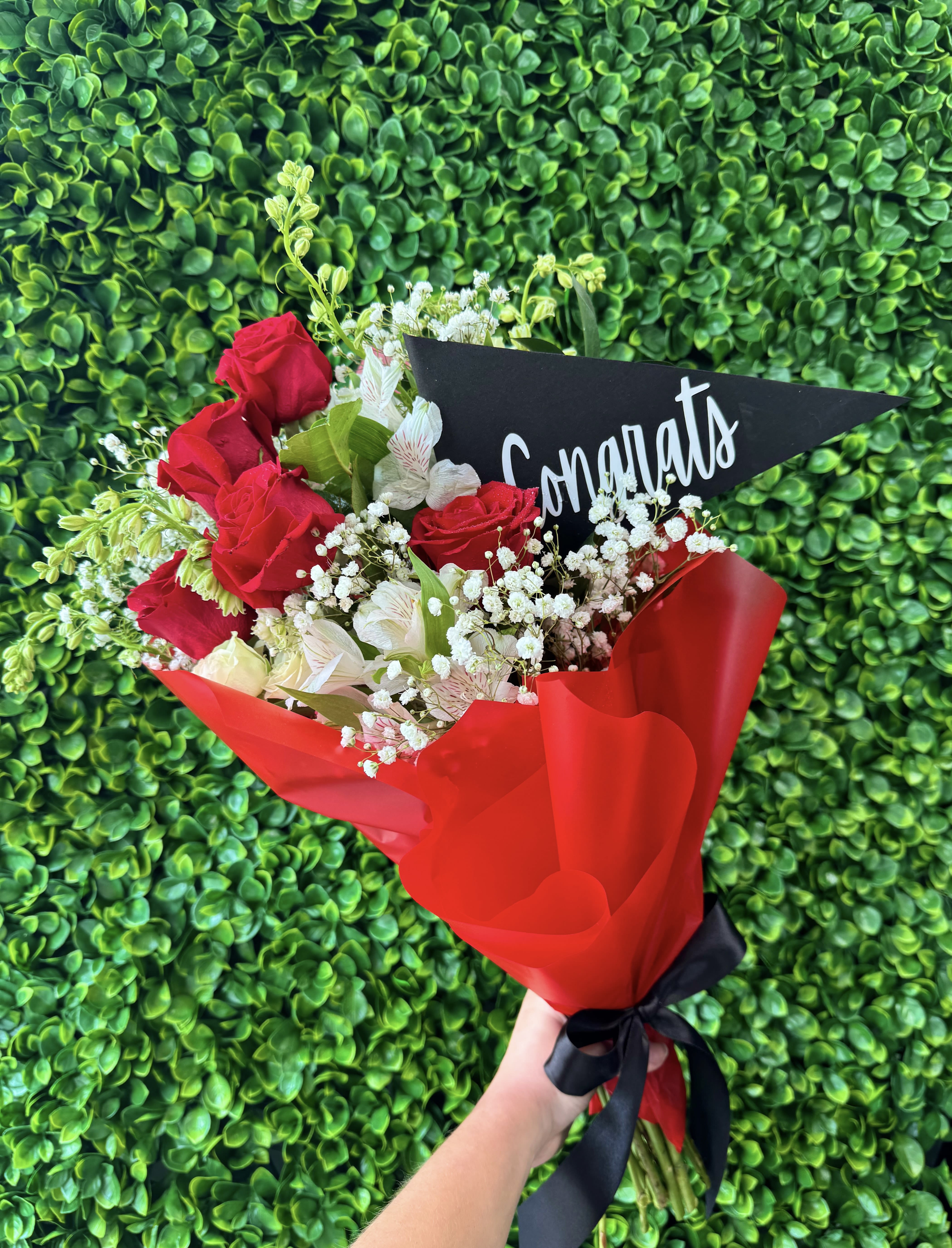 Bouquet of red roses and white flowers with a congratulatory card