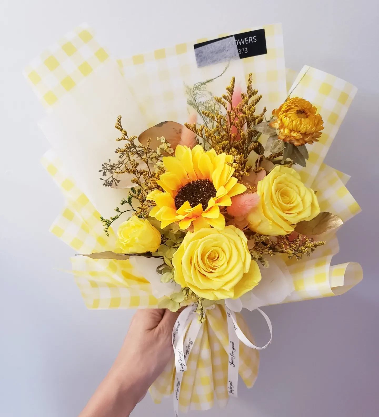 Yellow rose and sunflower bouquet wrapped in checkered paper
