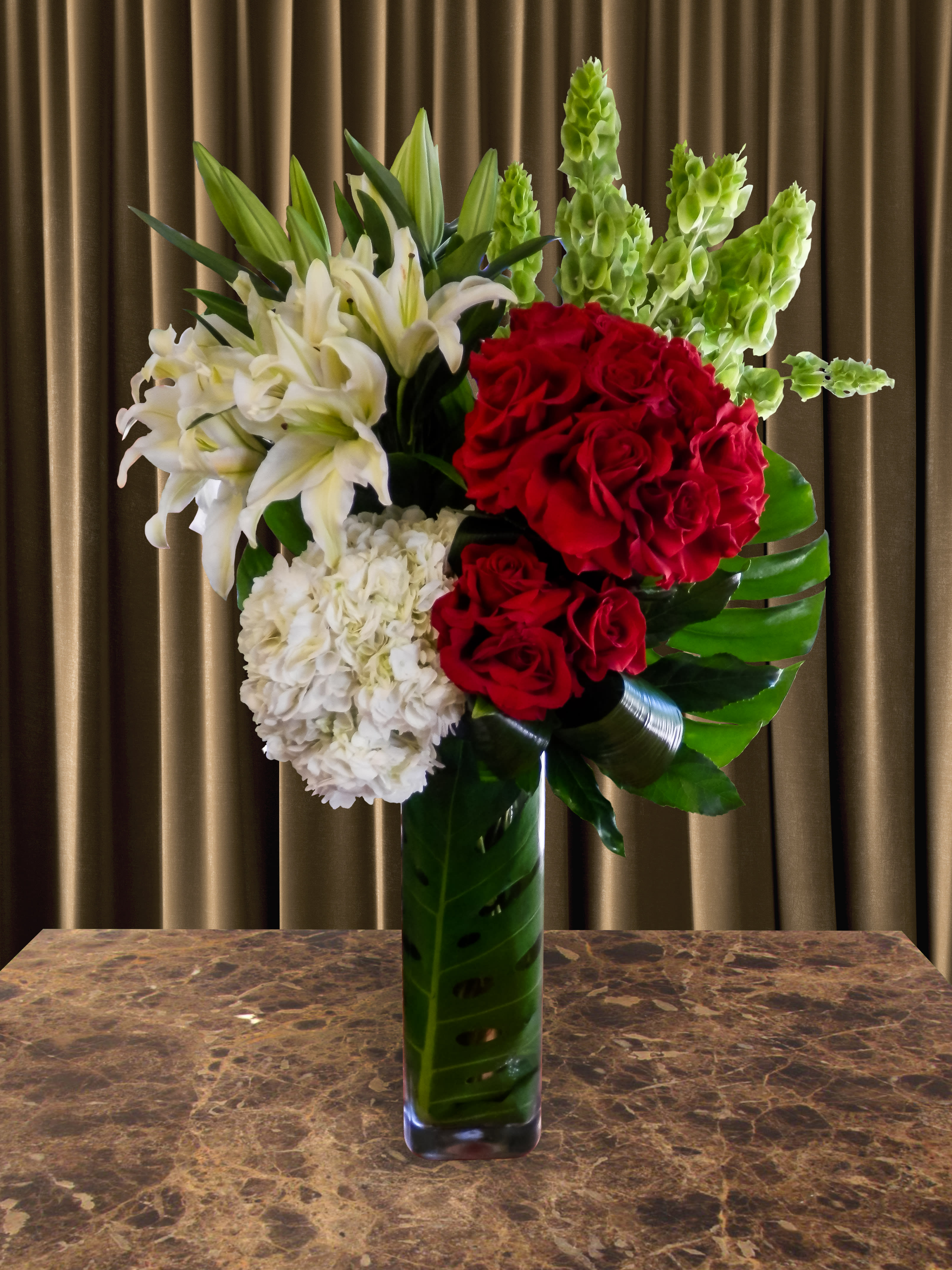 Red roses and white lilies arranged in a tall glass vase