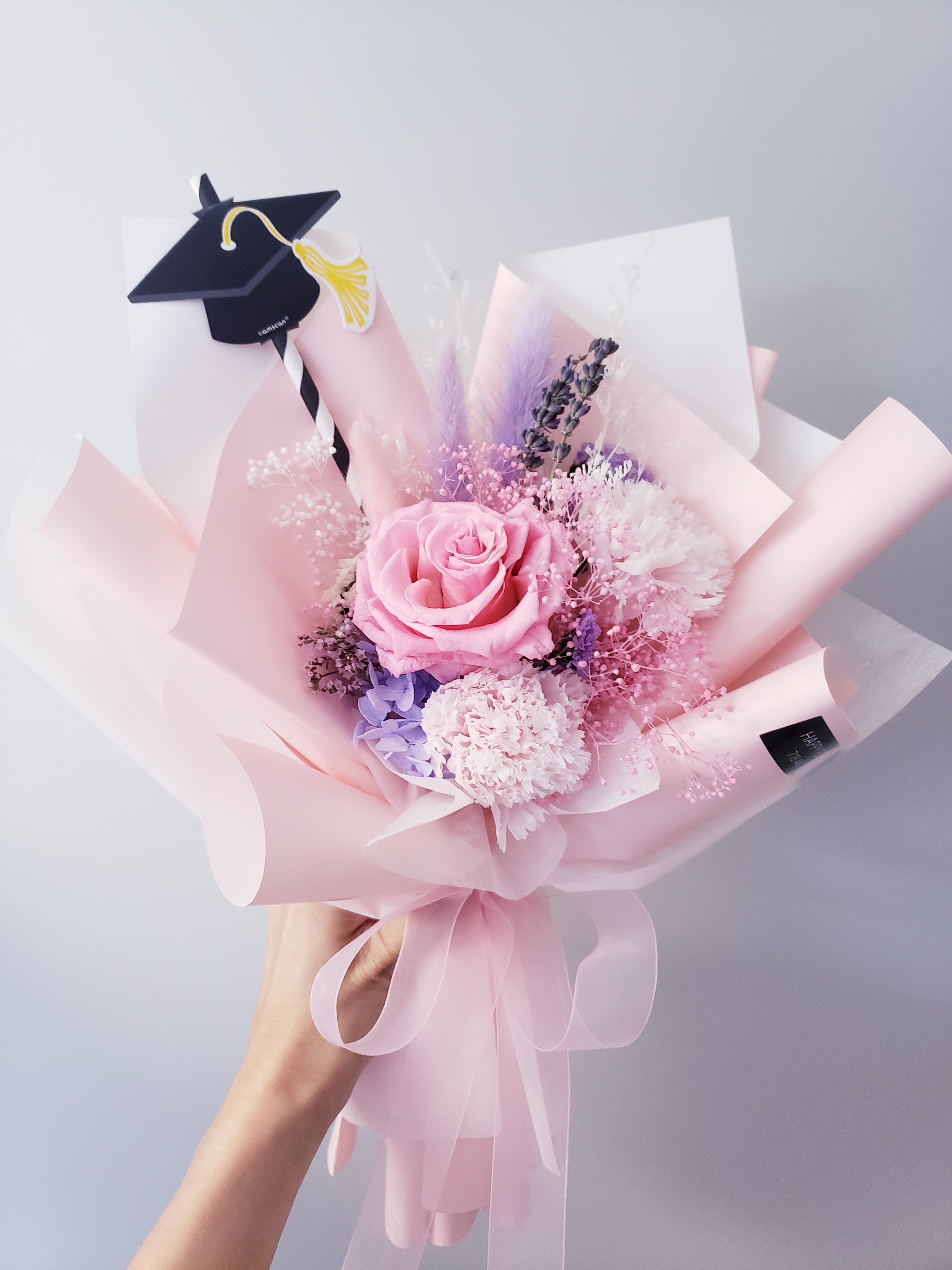 Pink rose bouquet with a graduation cap topper and pastel wrapping