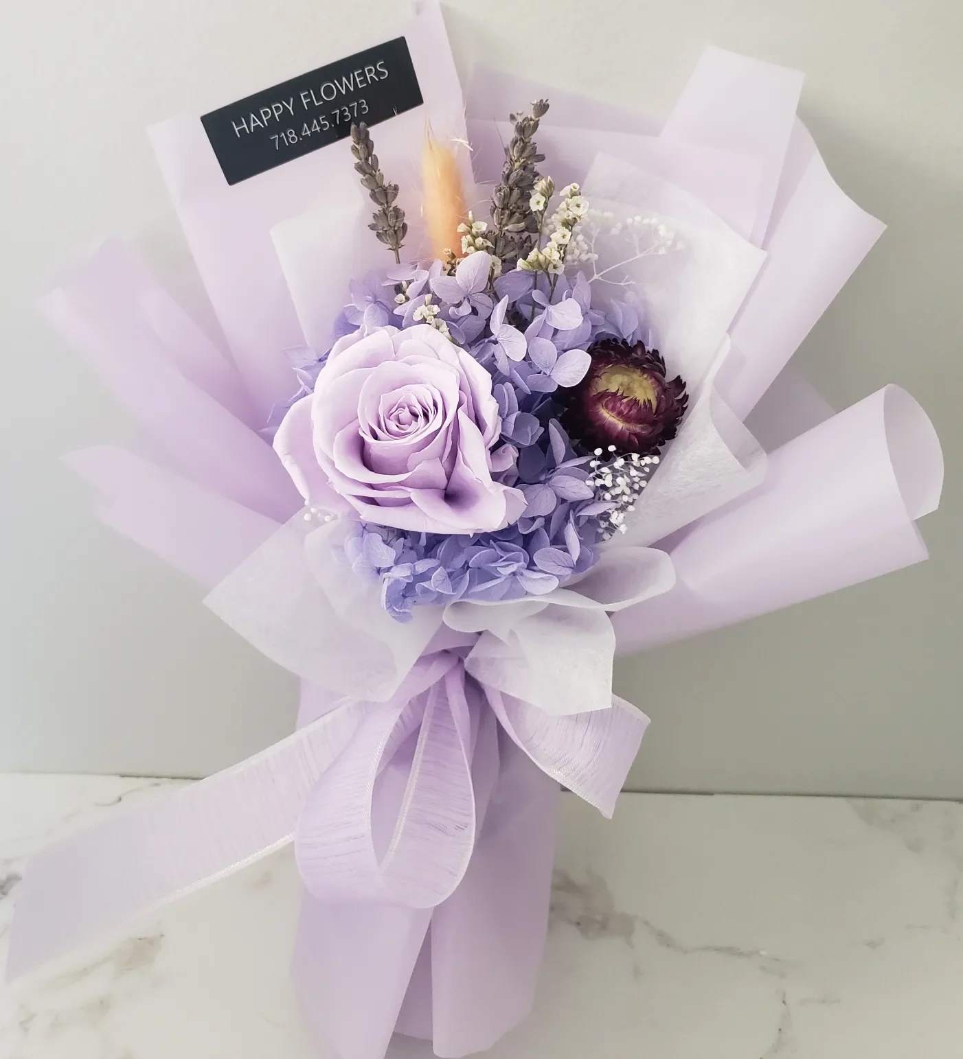 Lavender bouquet with a large rose and wrapped in pale purple paper