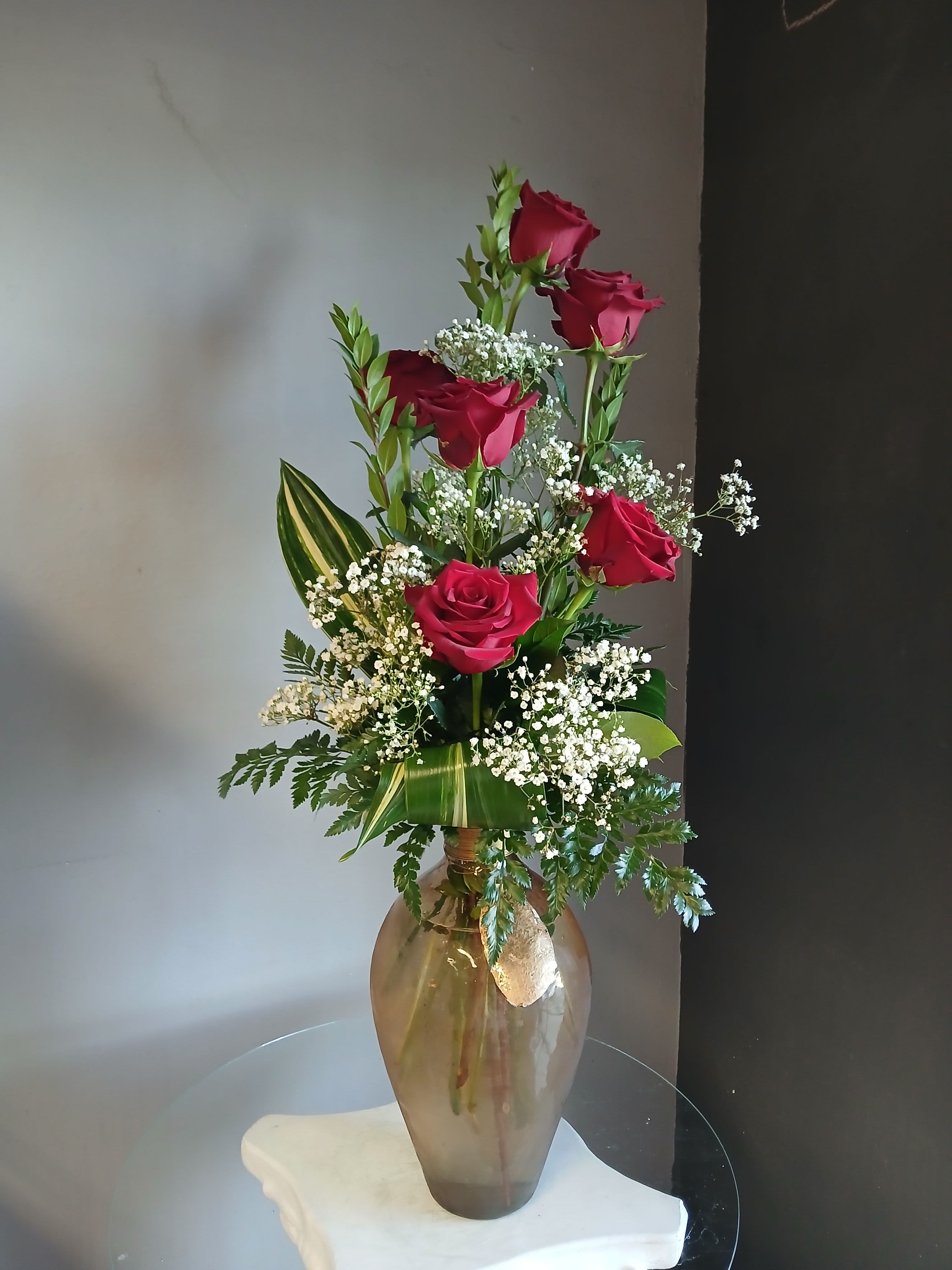 Tall vase arrangement of red roses with white baby's breath