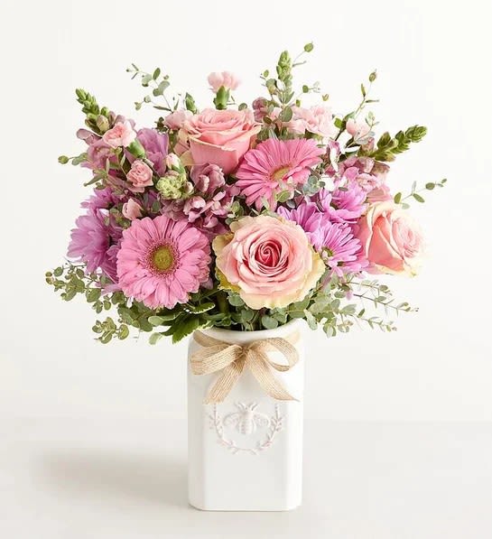 Honey Bee Buzz Summer - The Honey Bee Buzz for Mom arrangement , made with pink roses, lavender daisy , Lavender snap , Pink gerbera , arrange in a white ceramic vase tie on a burlap ribbon. To surprise mom for mother's day 