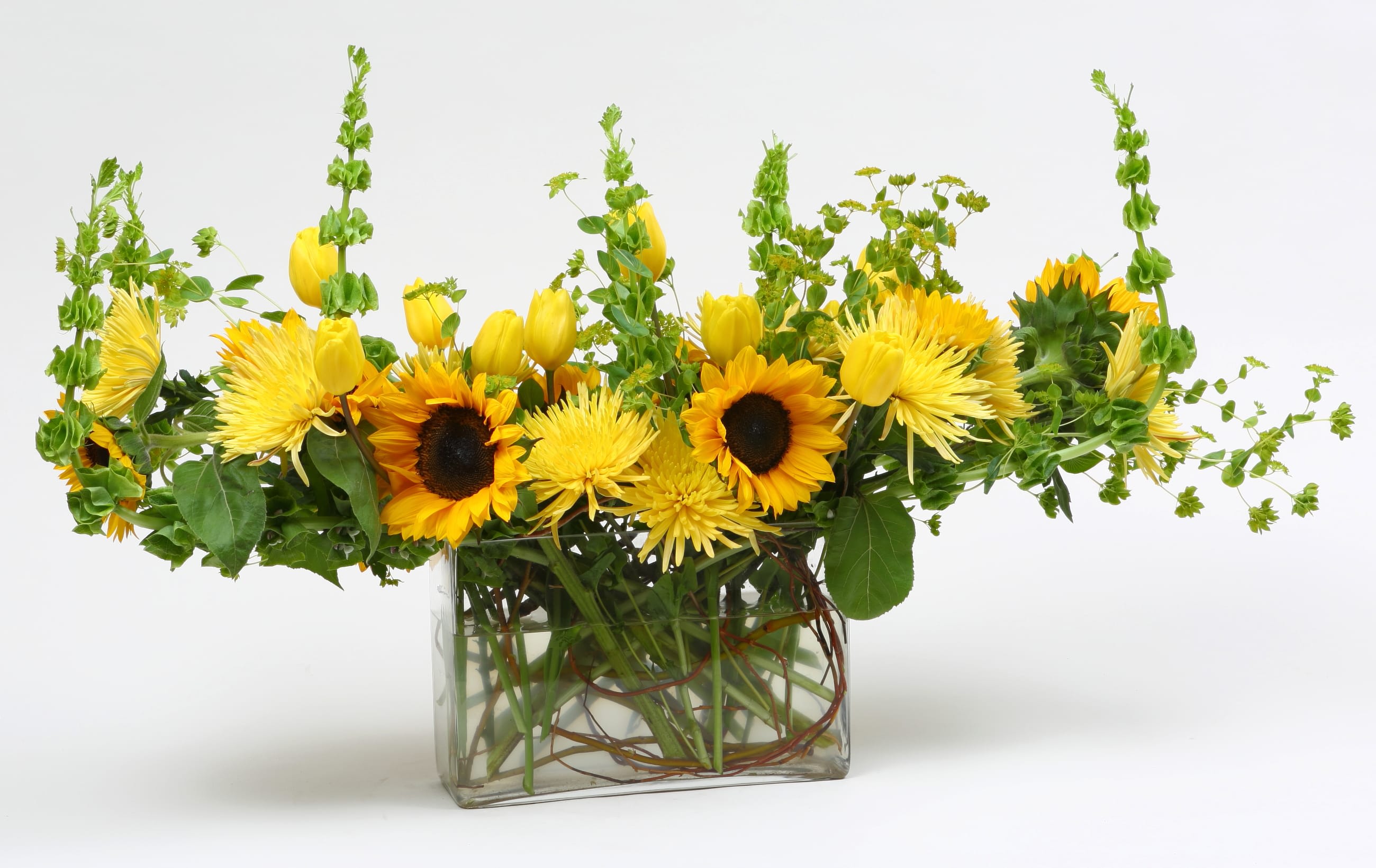 Yellow sunflowers and tulips in a clear glass vase