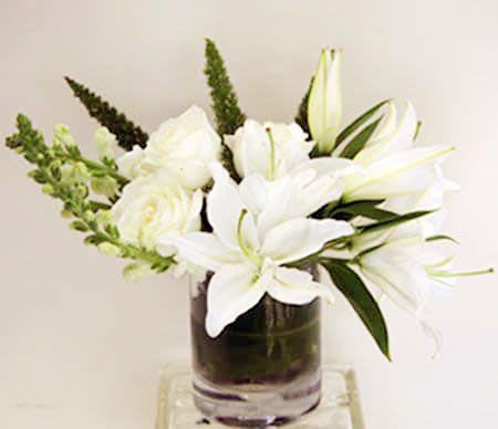 White lilies and roses arranged in a clear glass vase