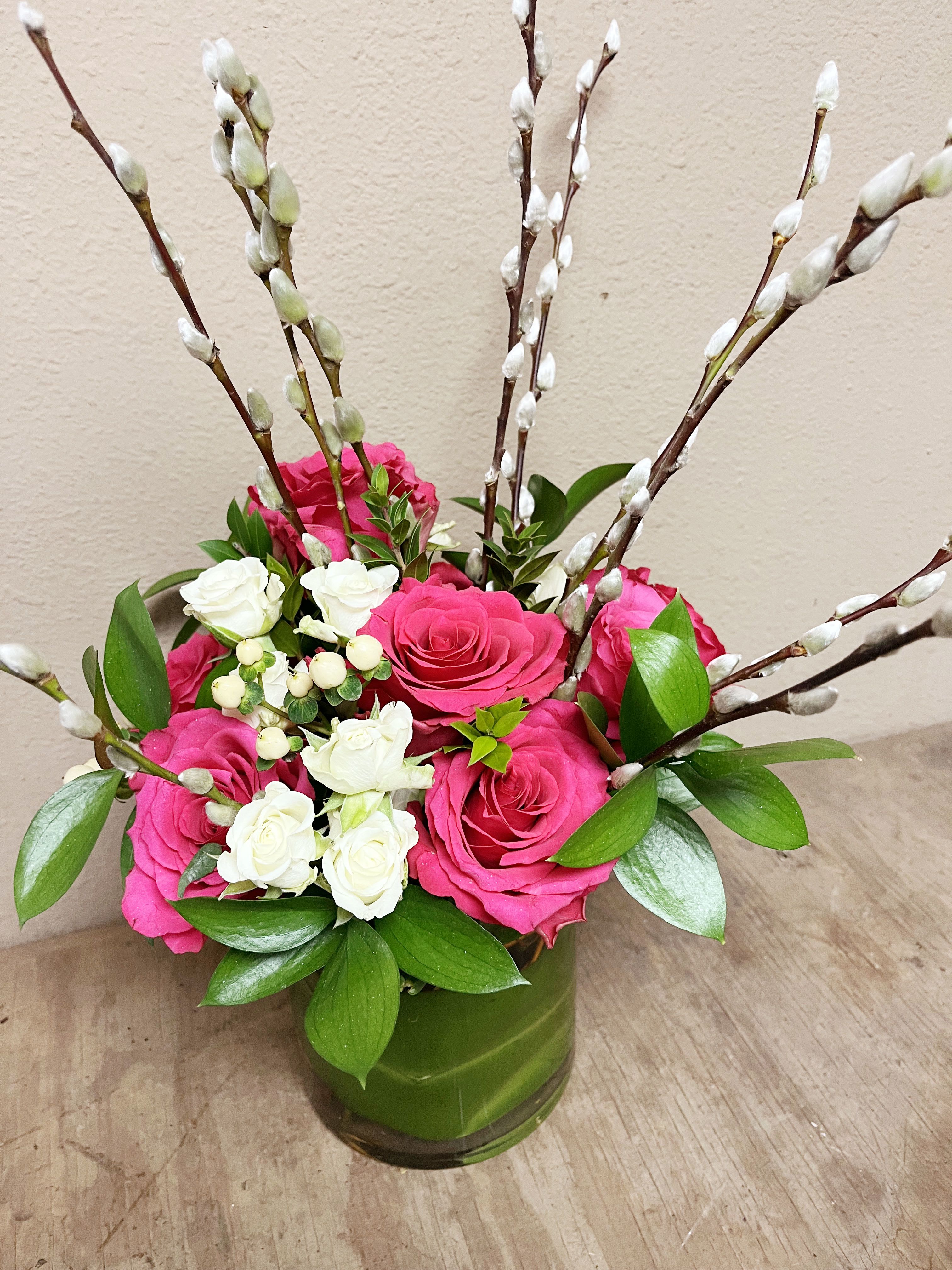 Pink and white roses in a green vase with pussy willow branches