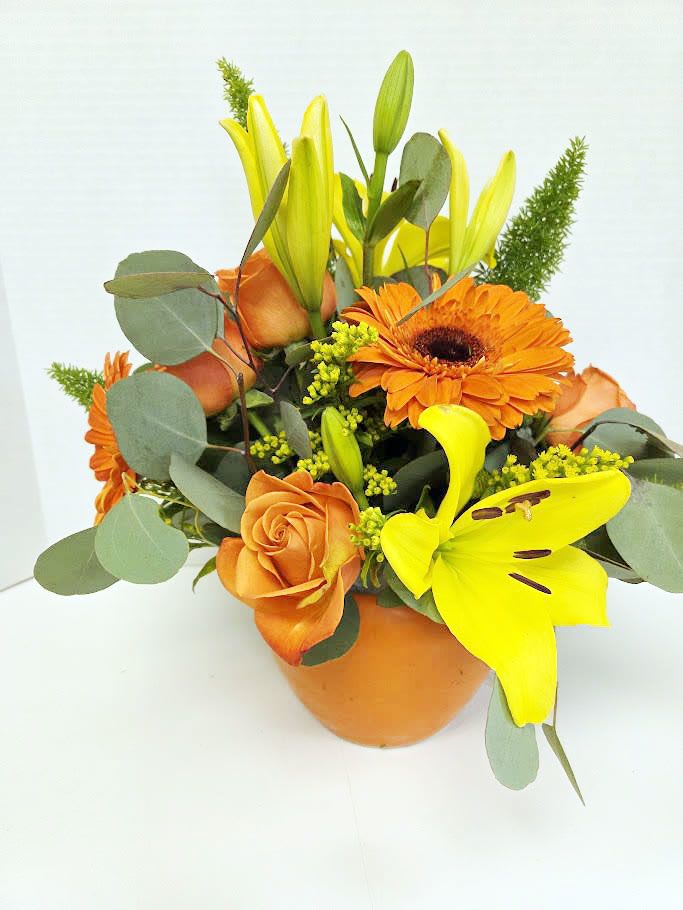 Orange and yellow bouquet with lilies, roses, and gerbera daisies in a vase