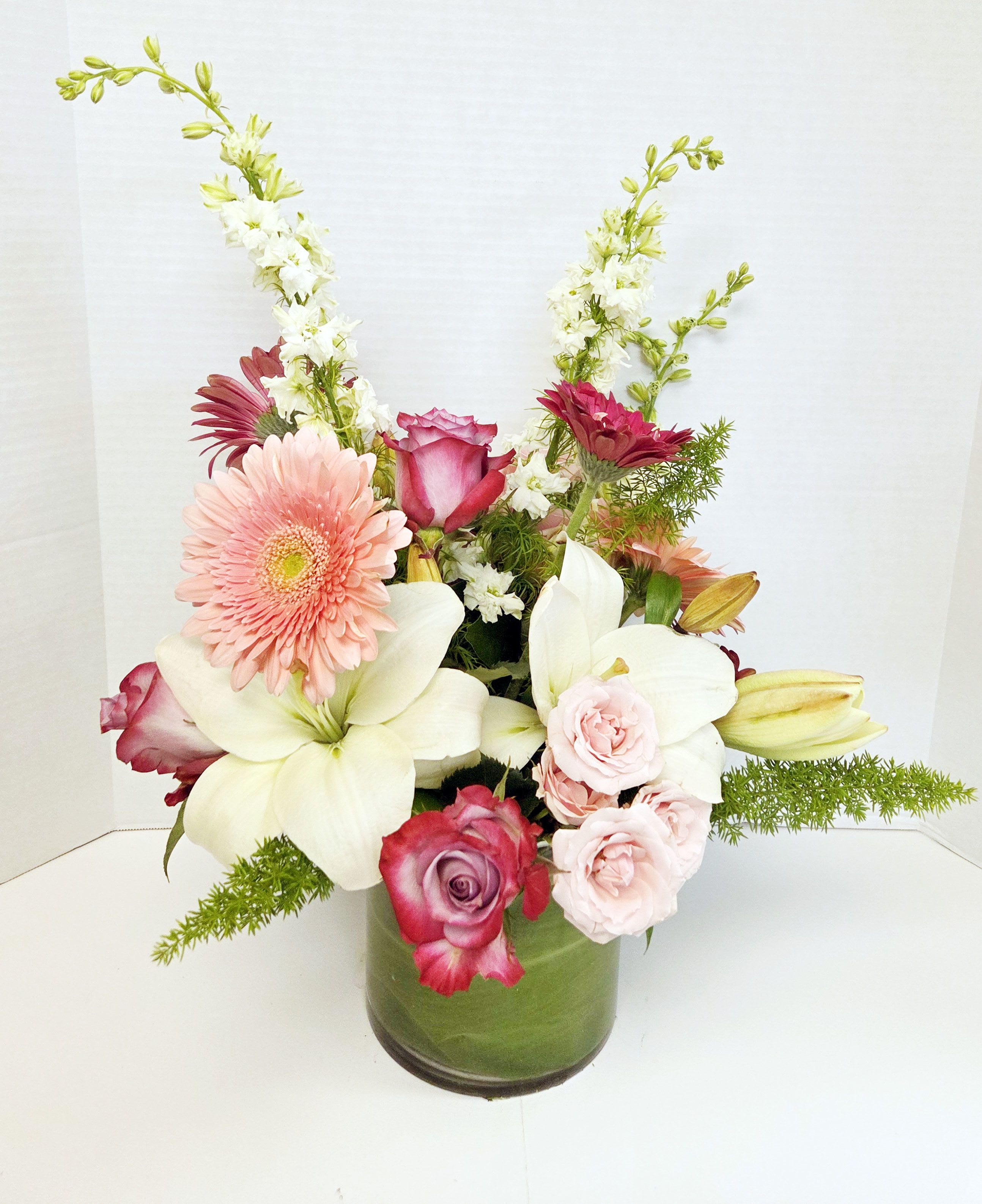 Mixed bouquet in a green glass vase with pink, white, and burgundy flowers