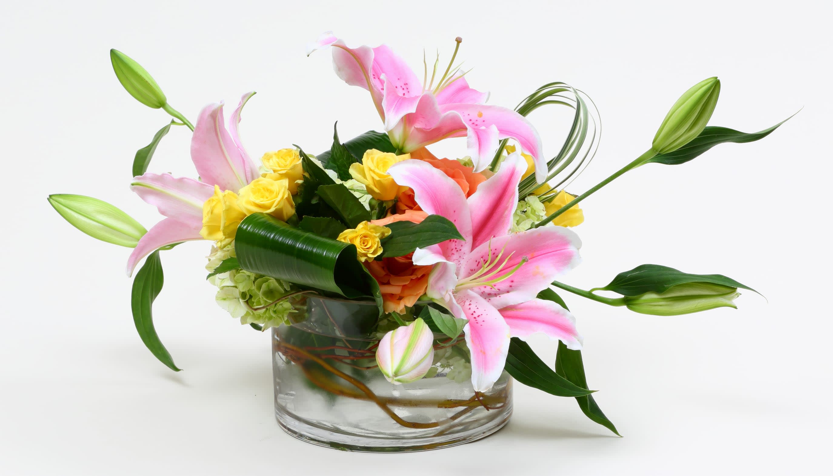Pink lilies and yellow roses arranged in a clear glass vase