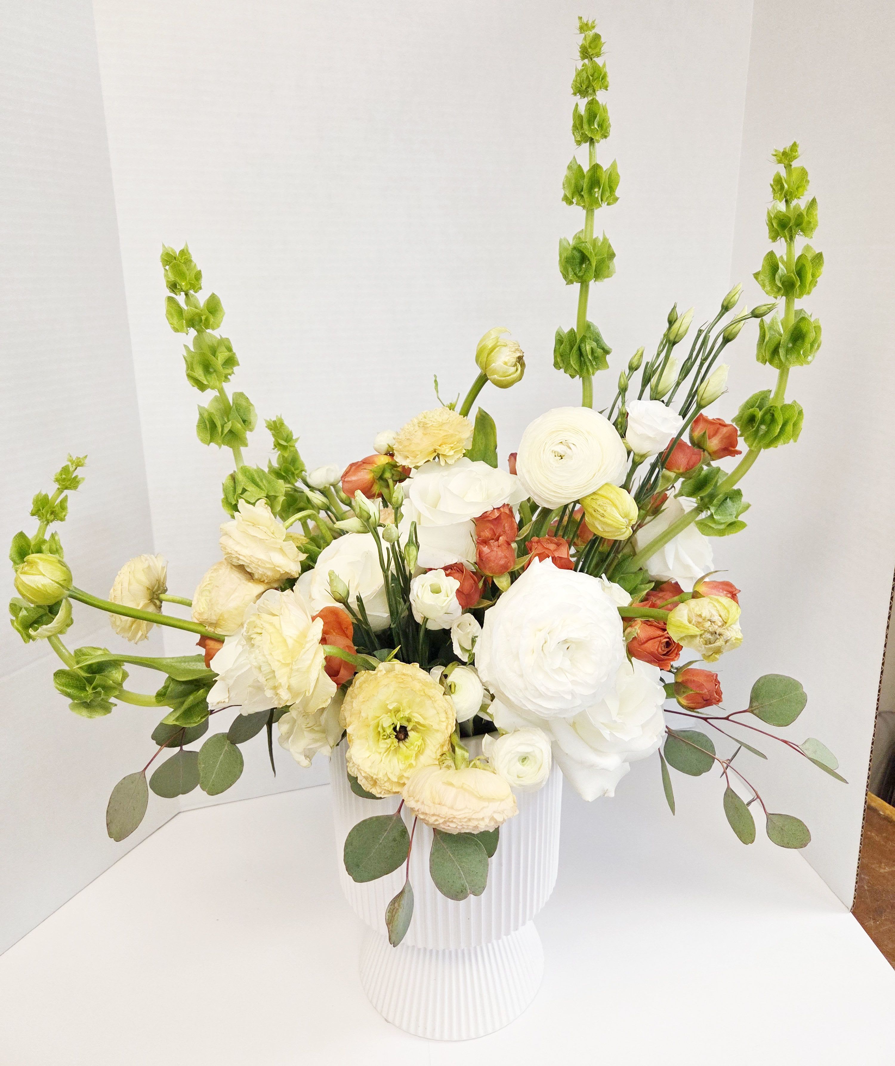 White and pale yellow floral arrangement in a ribbed white vase