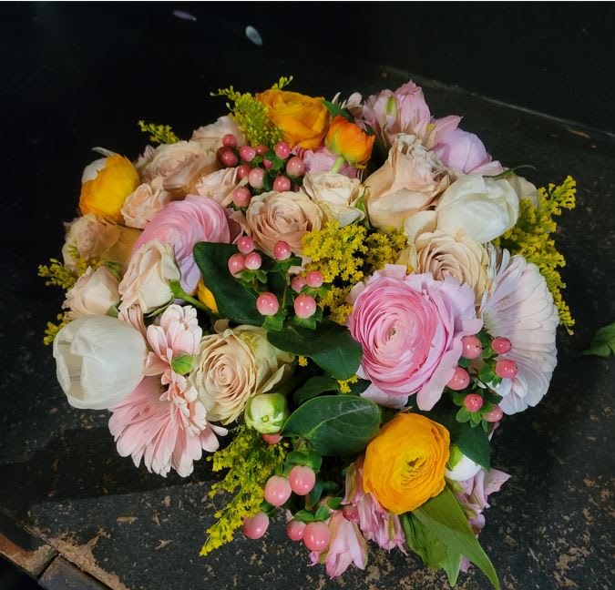 Bouquet of pink, cream, and yellow flowers with berry accents
