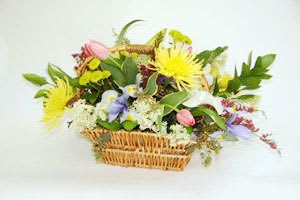 Mixed flower arrangement in a wicker basket with yellow and pink blooms