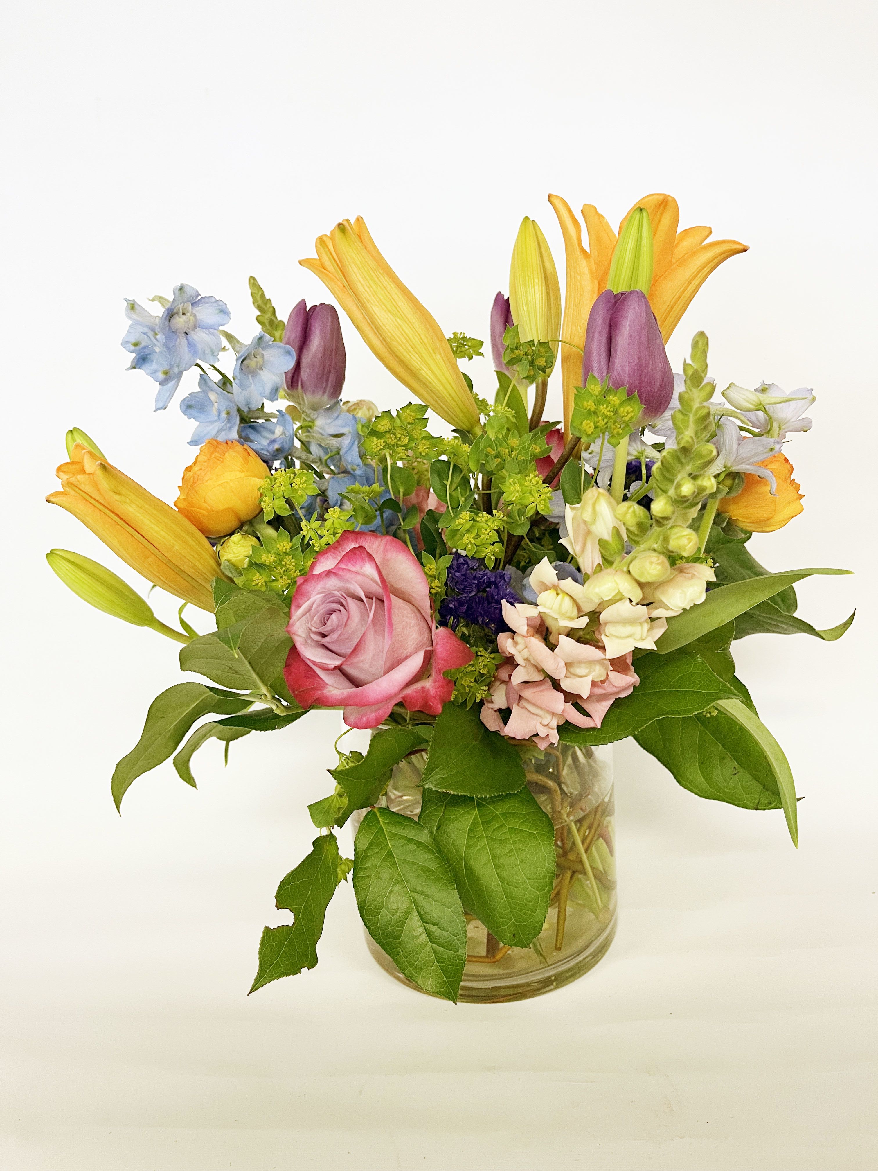 Mixed bouquet with roses, lilies, and snapdragons in a glass vase