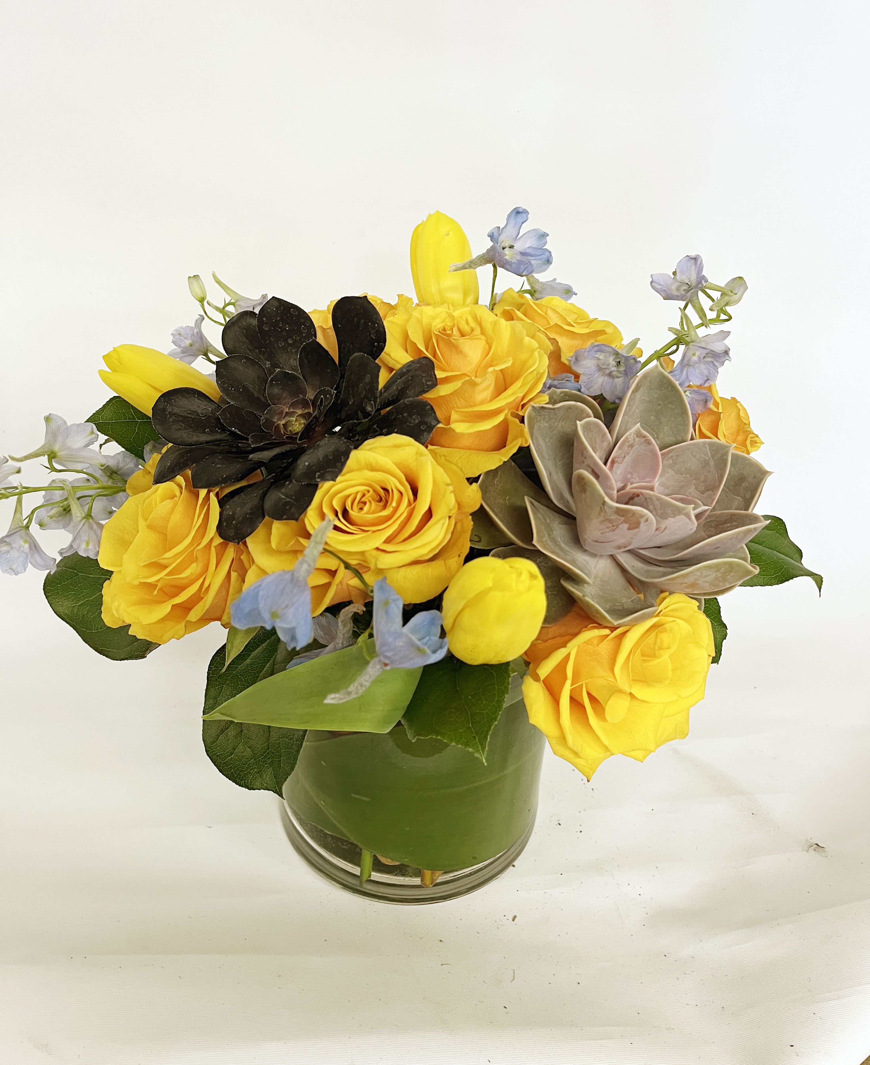 Yellow roses and succulents arranged in a glass vase