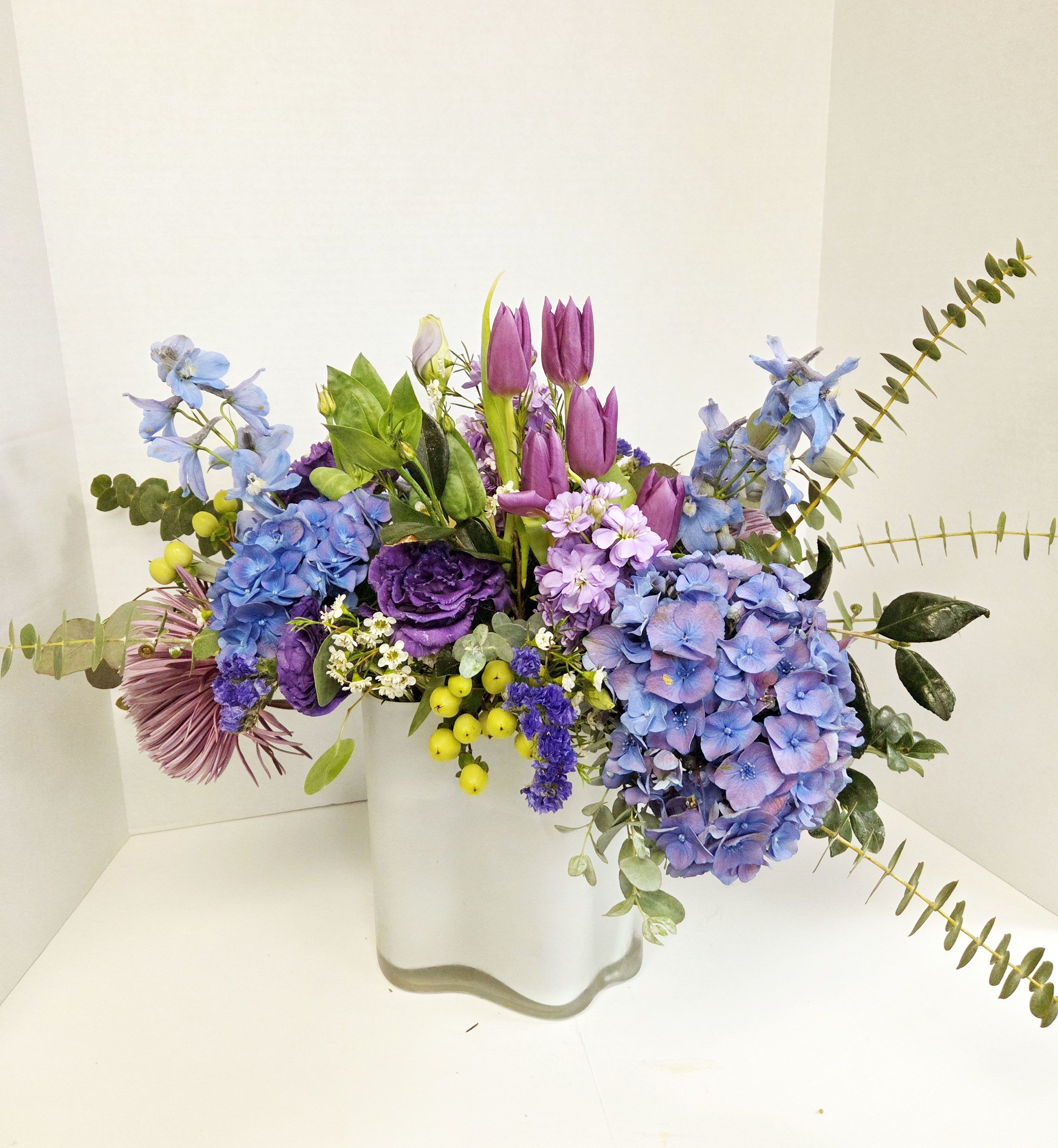 Purple and blue mixed bouquet in a white vase