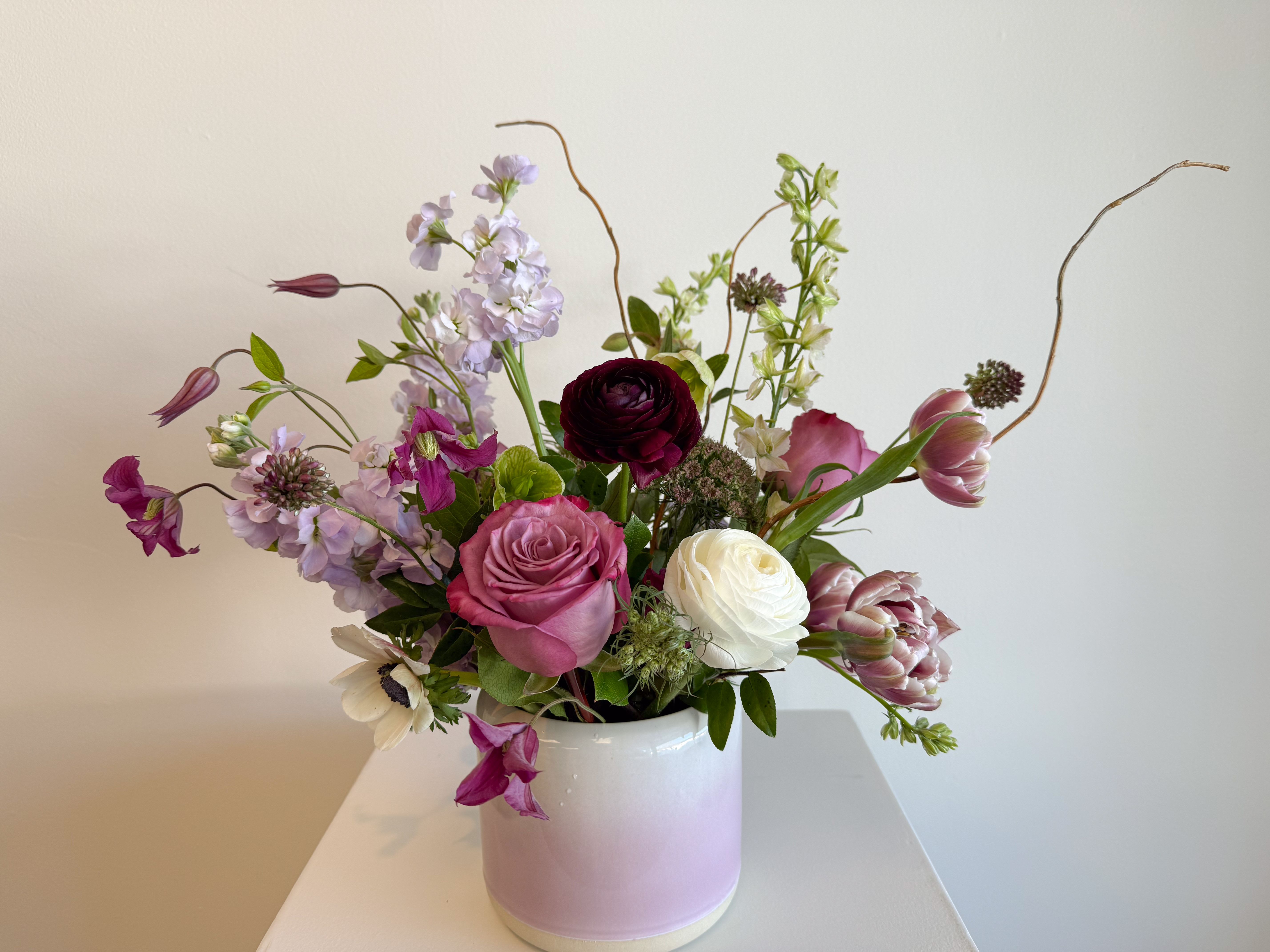 Mixed pink, white, and lavender flowers in a white vase