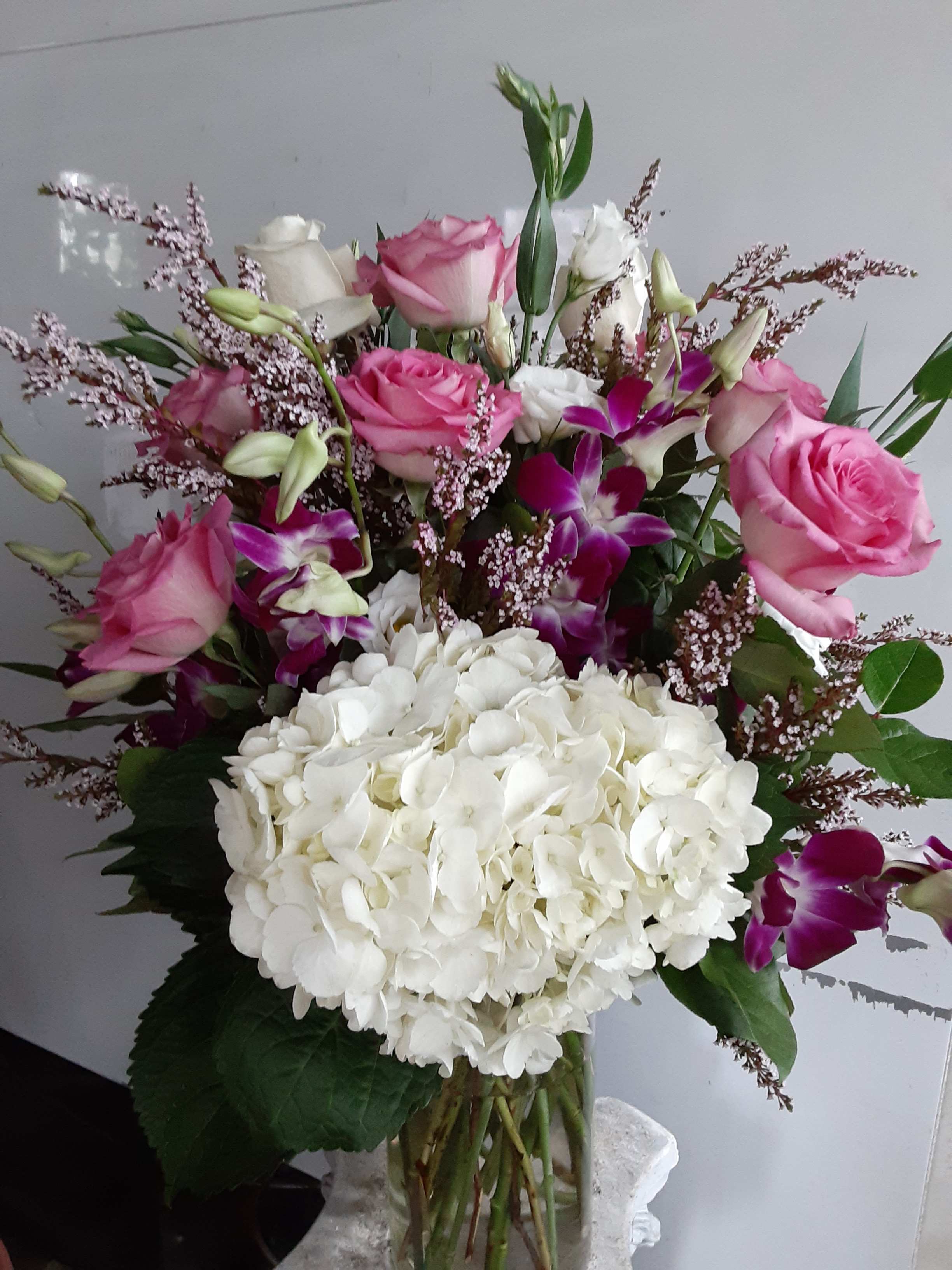 Bouquet of pink roses, white hydrangea, and purple orchids in a vase