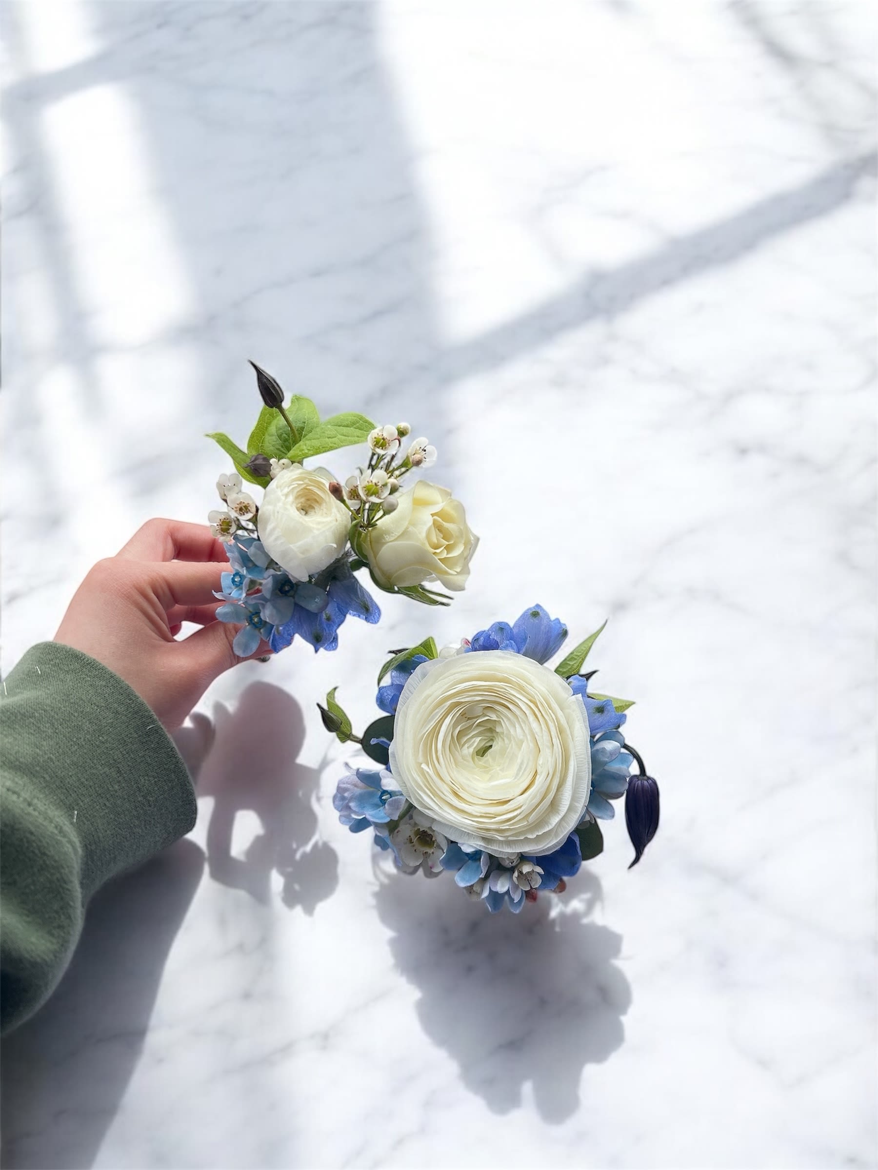 Two small floral wedding pieces with white blooms and blue accents