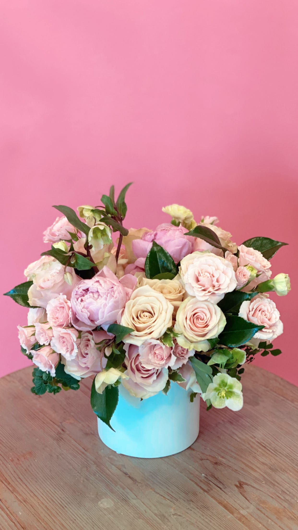 Pink and cream rose bouquet in a light blue vase